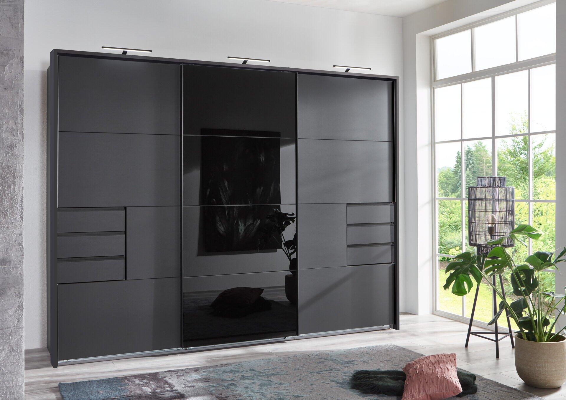 Schwebetürenschrank Saigon mit durchgängiger Glasfront und Spiegelbereich, der einen Blick in einen Garten freigibt, sowie drei Schubladen und weiteren Fächern.