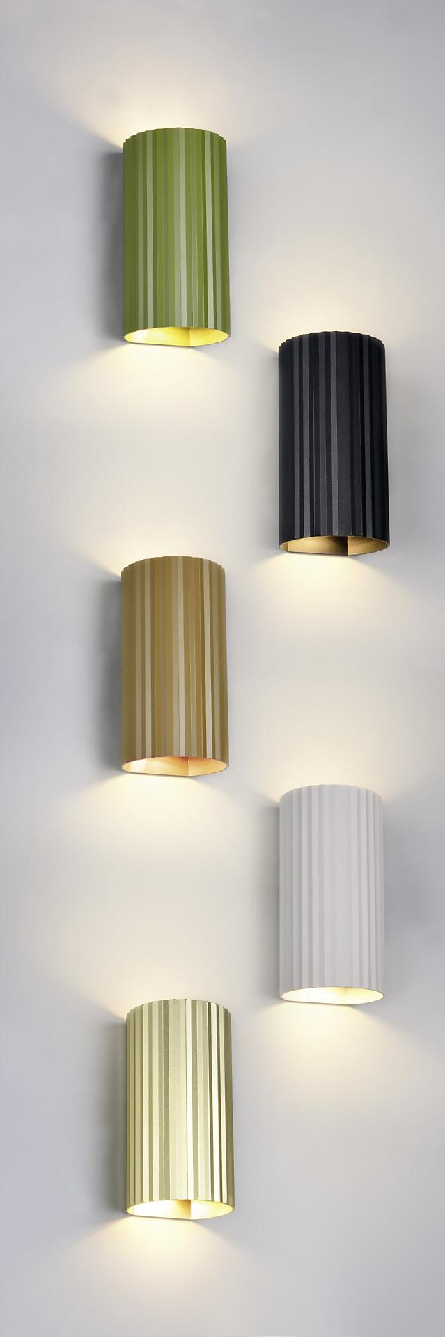 Wandleuchte Soka in Gold, Schwarz und Weiß mit vertikalen Rillen und zylindrischem Design, frontal und detailreich abgebildet.
