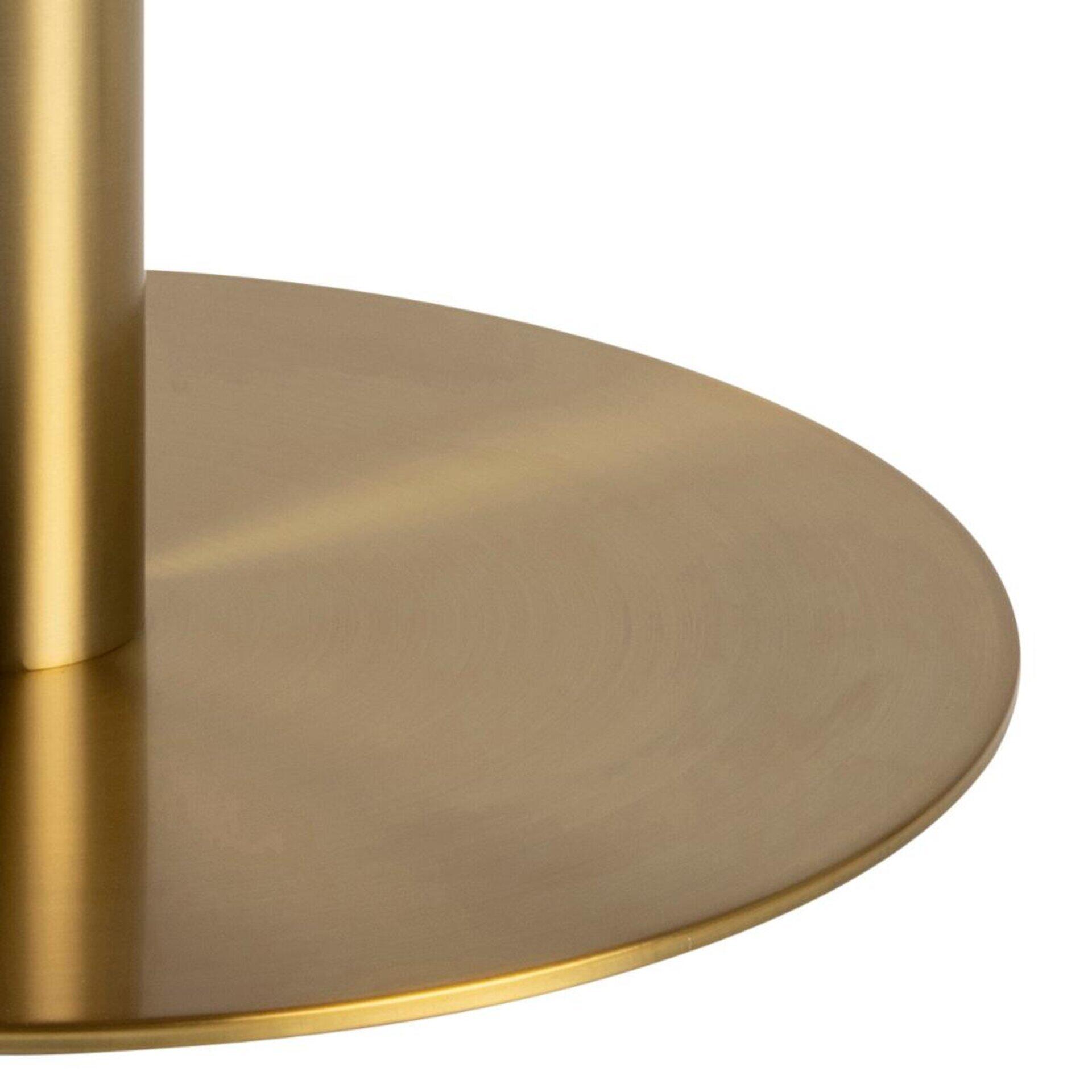 Detailaufnahme der gewölbten, goldfarbenen Tischplatte des Couchtisches Corby, die durch ihre Rundung und Reflexionen das Design betont.