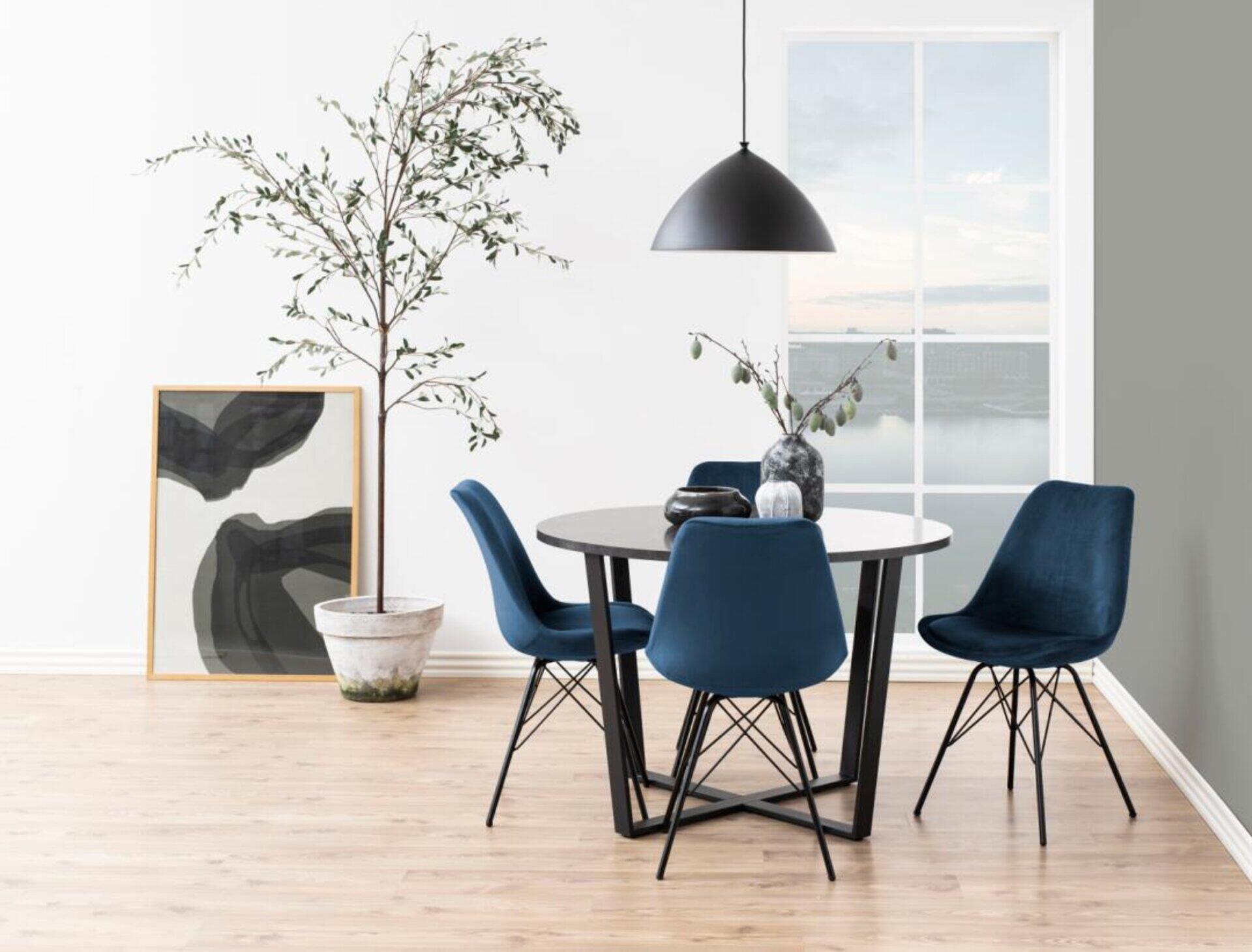 Esszimmerstuhl Eris mit blauer Samtbezug und schwarzen Metallfüßen, Teil einer modernen Essecke mit rundem Tisch und stilvoller Pendelleuchte.