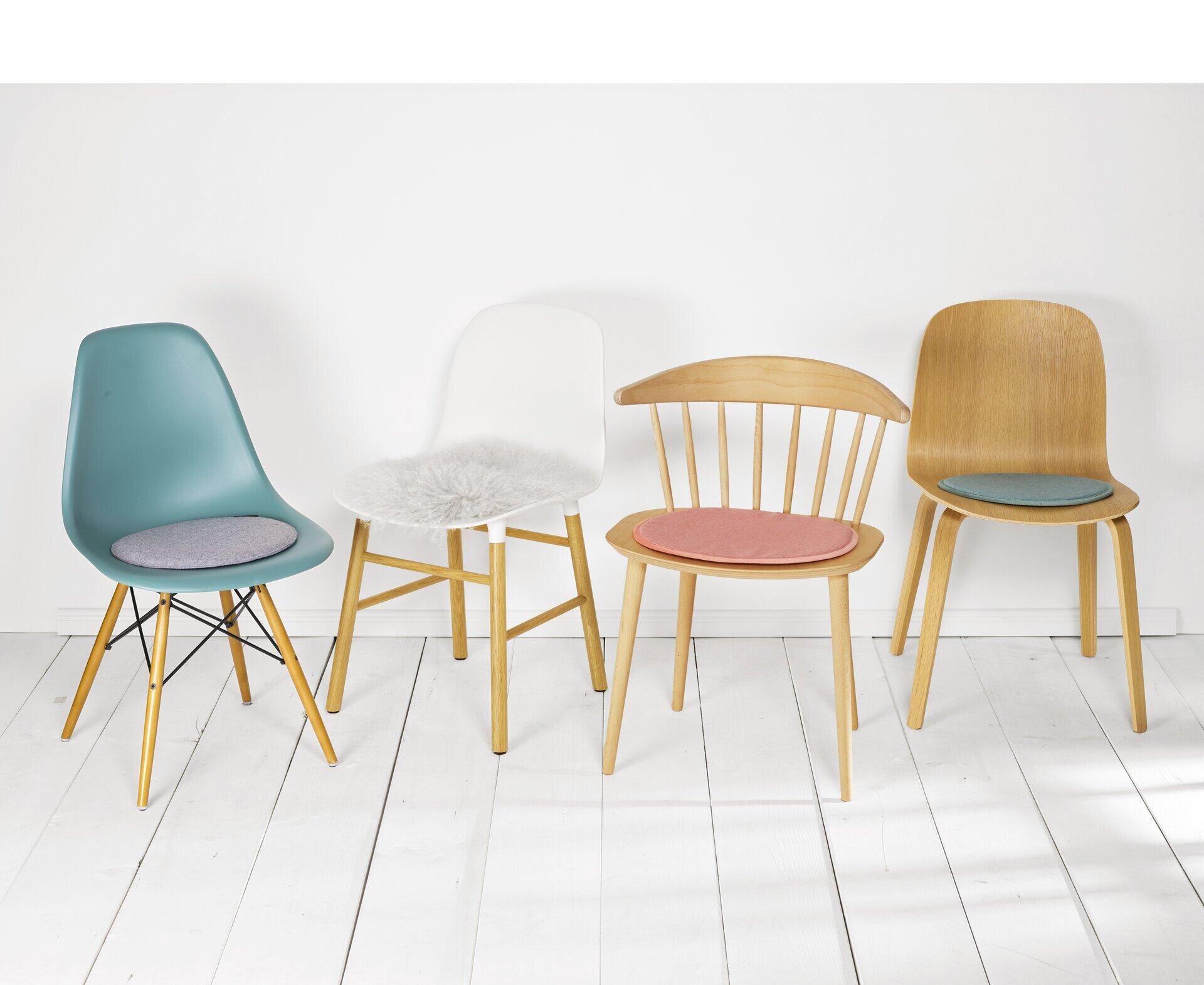 Vier Stühle mit unterschiedlichen Designs und ein pinkfarbenes Wende-Sitzkissen Avaro in einer frontalen Ansicht.