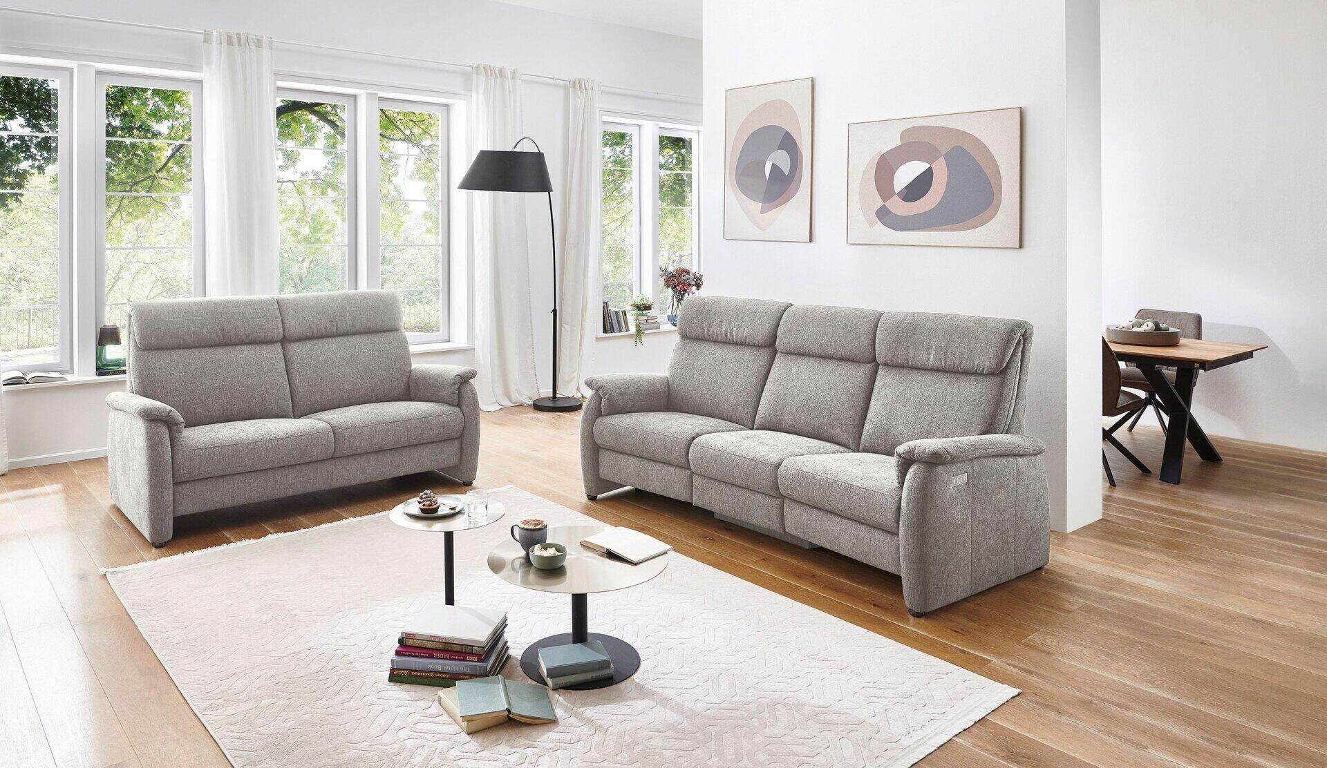 Trapezsofa 821 im Raumambiente mit niedrigem Rücken, breiten Armlehnen und horizontalen Nähten für eine gepolsterte Optik.
