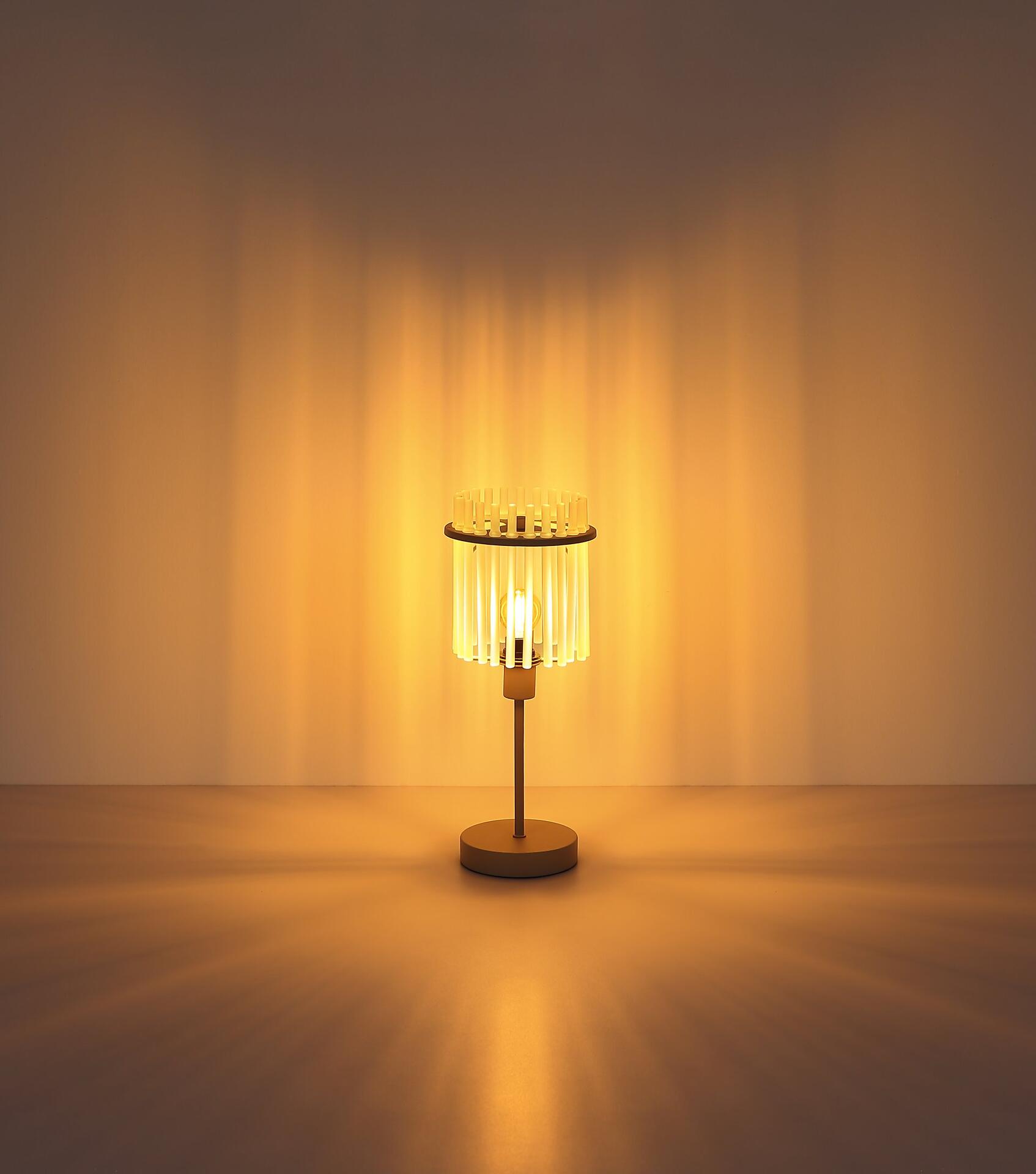 Tischleuchte GORLEY mit minimalistischem Design und Lampenschirm aus vertikalen Glasstäben, die ein warmes, diffuses Licht erzeugen, vor einem hellgelben Hintergrund.