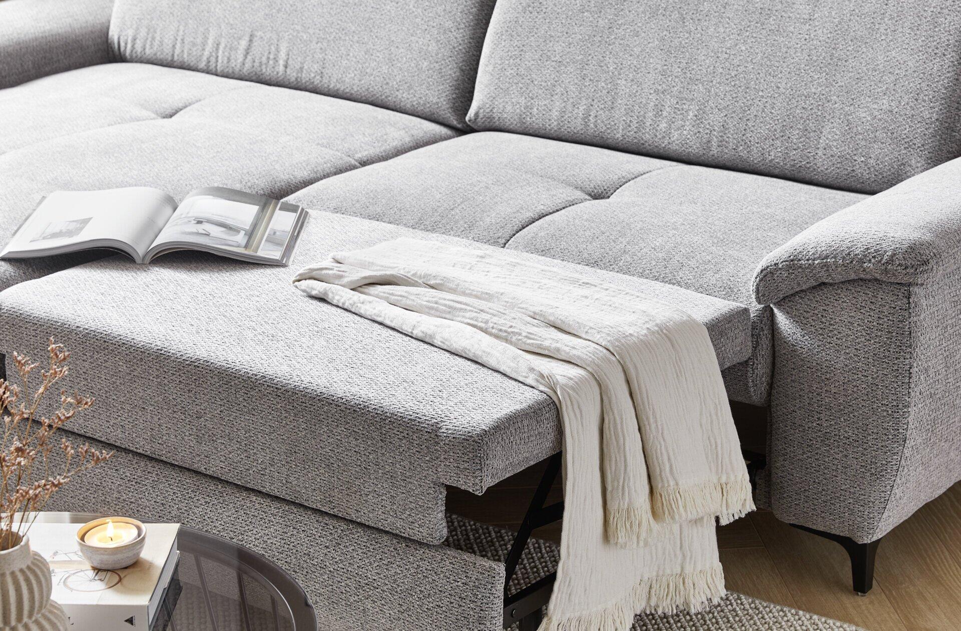 Ecksofa Retro mit ausgezogener Schlaffläche und übergeworfenem Laken, Detailaufnahme der Schlaffunktion.