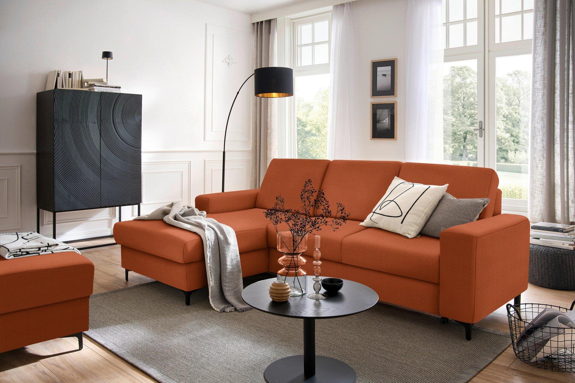 Ecksofa Balina in Orange mit Winkelfüßen aus Metall, leicht erhöhte Perspektive zeigt die gesamte Couch und angrenzende Möbelstücke im modernen Wohnzimmer.