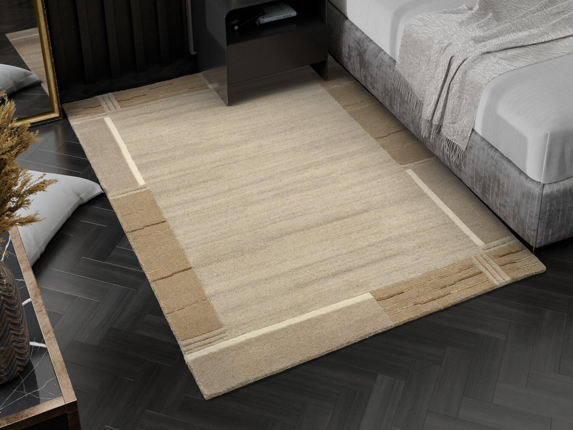 Handknüpfteppich Nanded mit geometrischem Muster und 17cm Florhöhe, fotografiert aus erhöhter Perspektive in einem Raum mit Fischgrätparkett und beigem Bett.