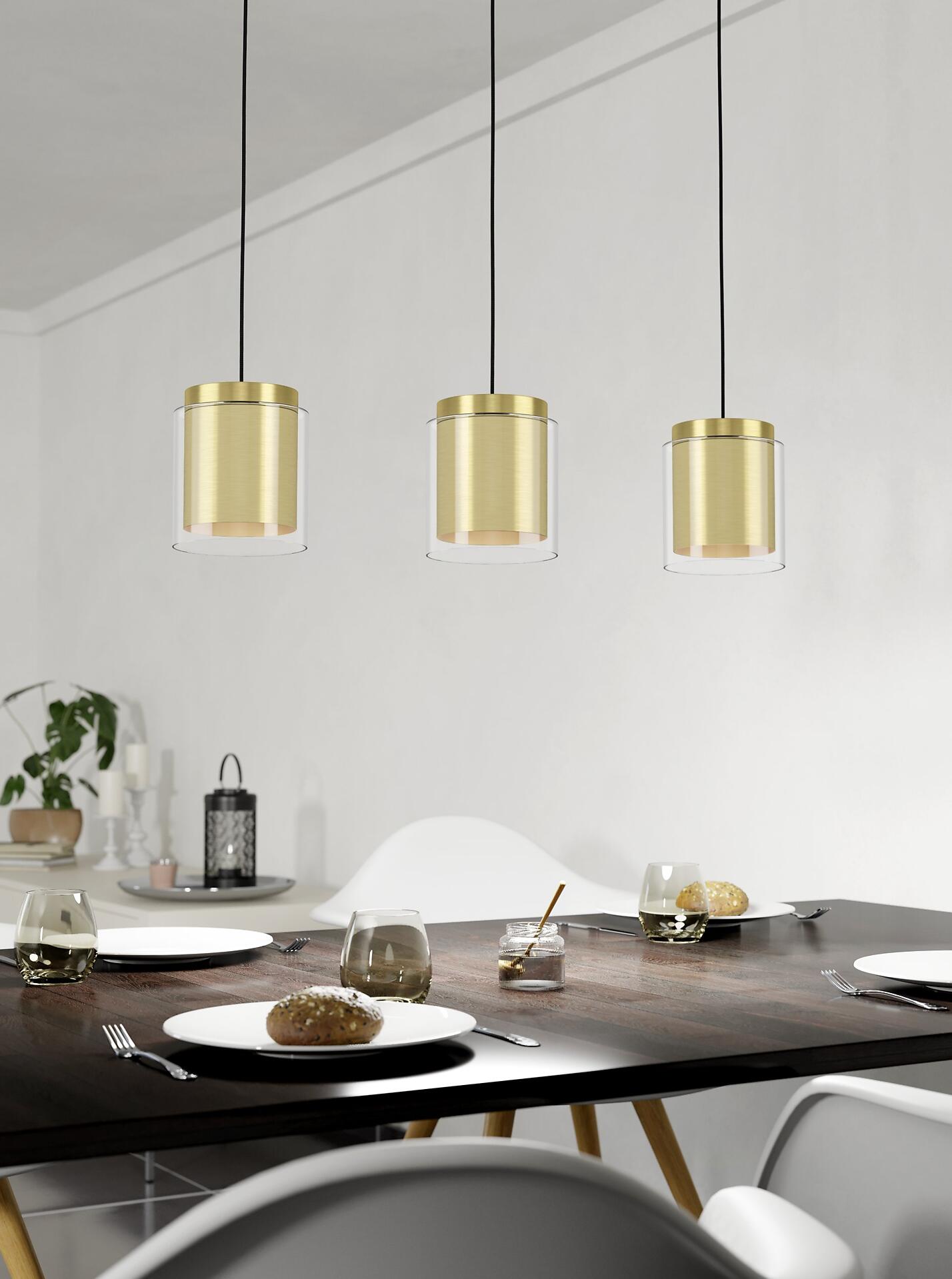 Pendelleuchten Lagunitas mit goldenem Zylinderkern und durchsichtigem Äußeren hängen über einem Essplatz mit Holztisch und Geschirr, aufgenommen aus erhöhter Perspektive.