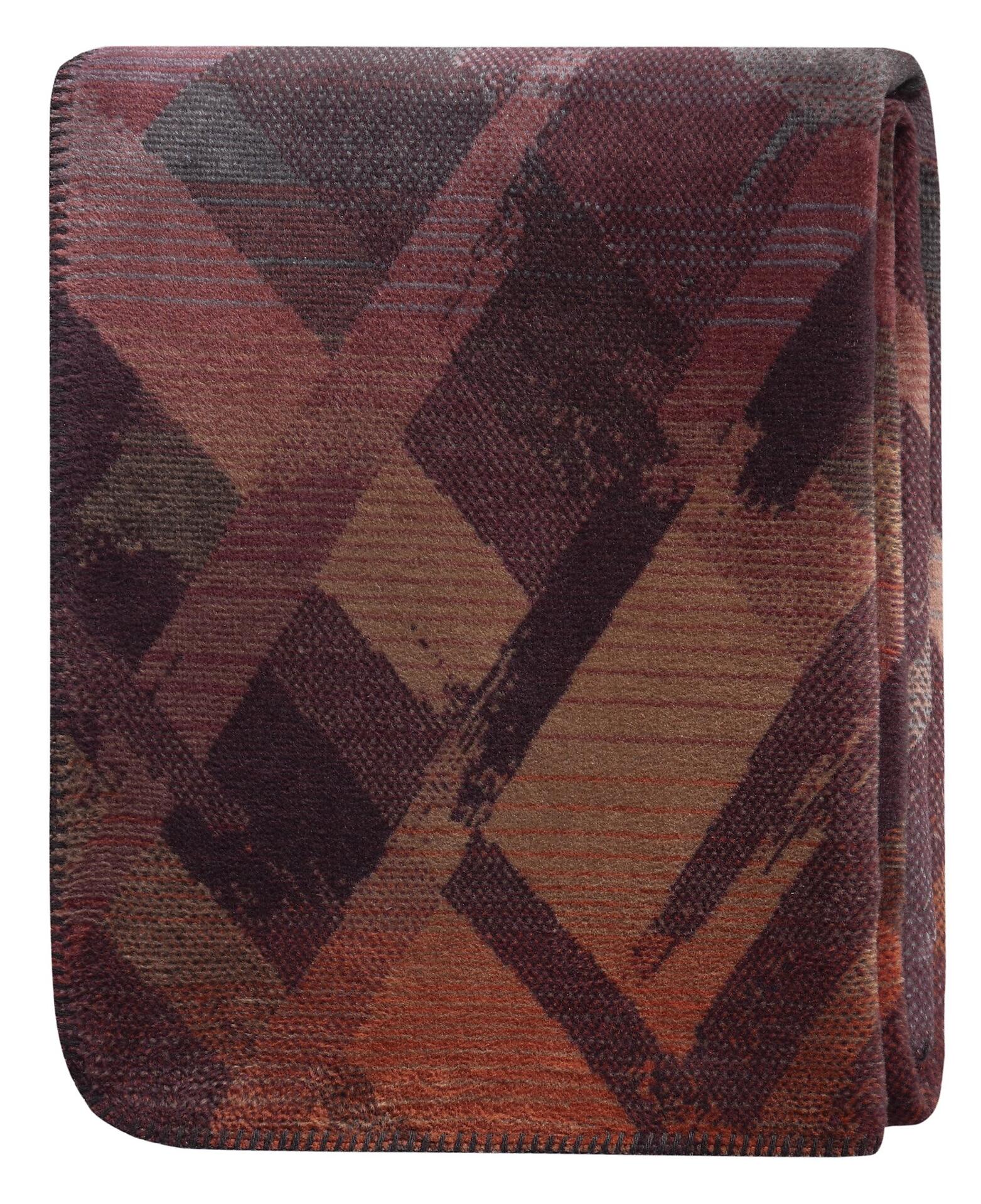 Detailaufnahme des garnet glow Wohndeckenmusters von Biederlack mit abstraktem, geometrischem Design in Braun-, Rot- und Orangetönen.