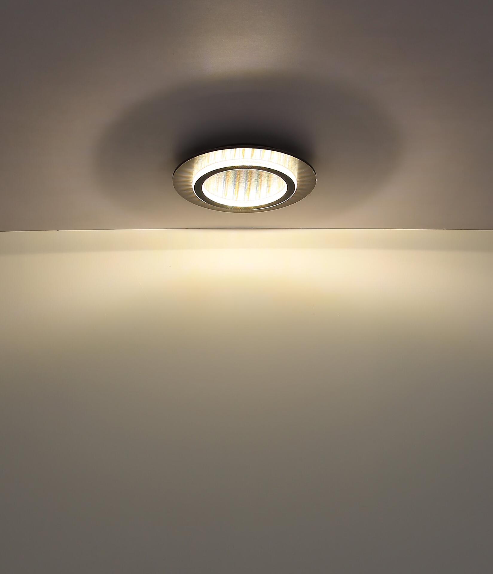 Deckenleuchte JAYDEN mit silbernem Rahmen und Kunststoffkristallen, eingebettet in einer Wand, zeigt das warme Licht und den hellen Lichtfleck auf der Wand.