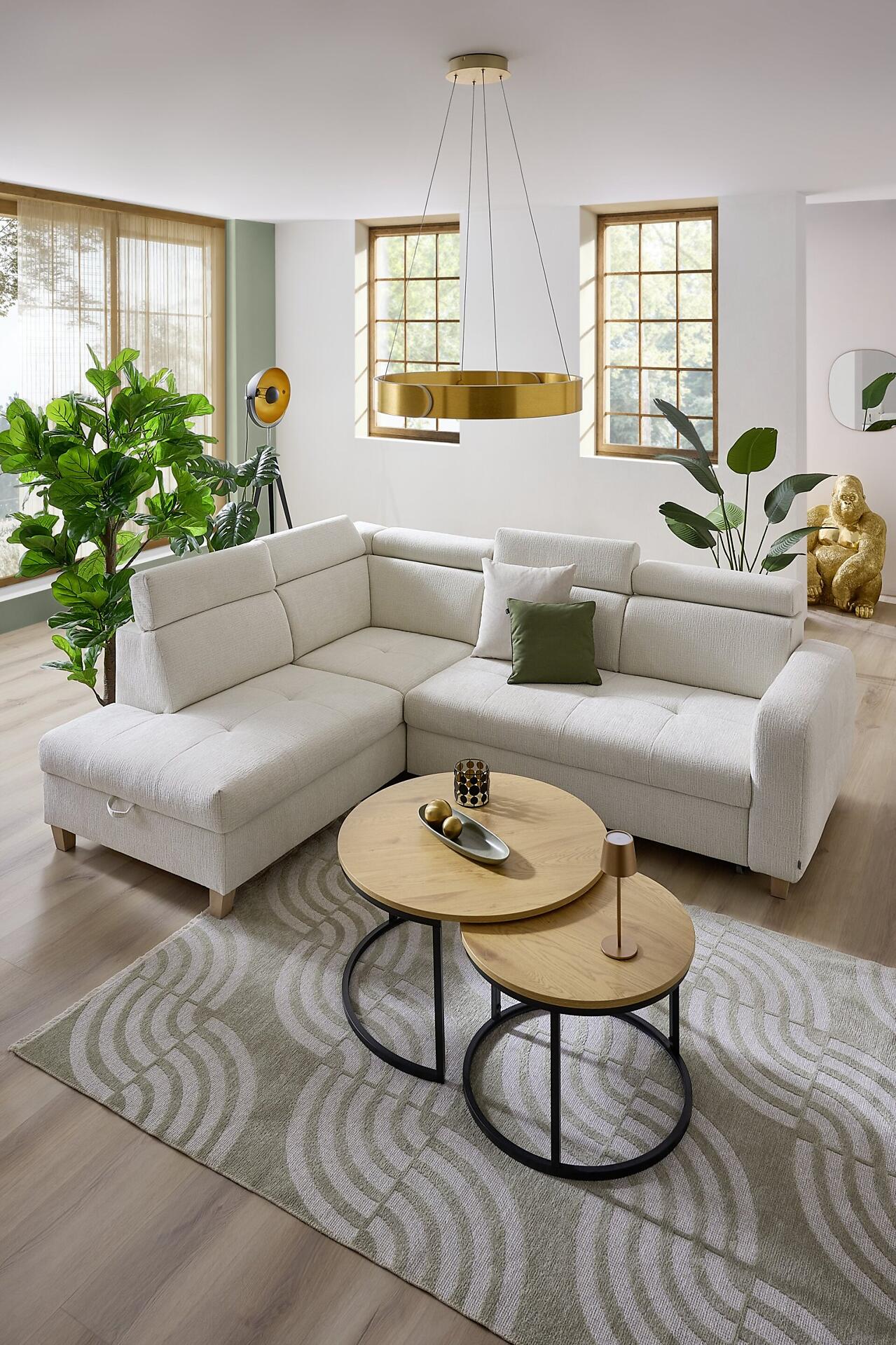 Ecksofa Saragossa in Beige mit abgewinkelter Rückenlehne und relaxähnlicher Neigung, präsentiert in einer gemütlichen Wohnszene mit Teppich, Couchtischen und Dekoelementen.