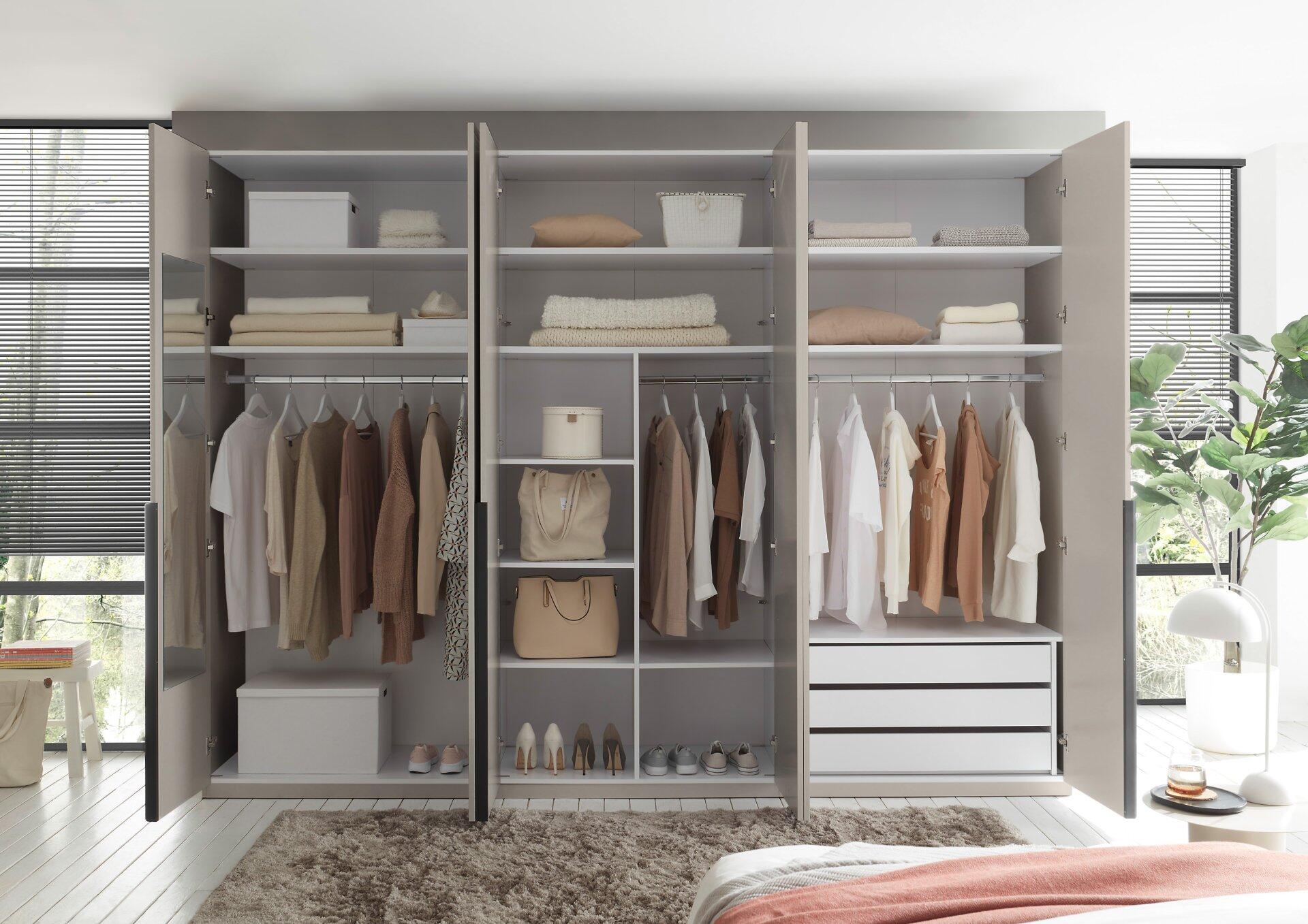 Geöffneter Kleiderschrank Camoleo mit 6 Türen, Schrankinneneinteilung, Hängegarderobe, Schubladen und Spiegel in der linken Tür, dargestellt aus frontaler Perspektive.