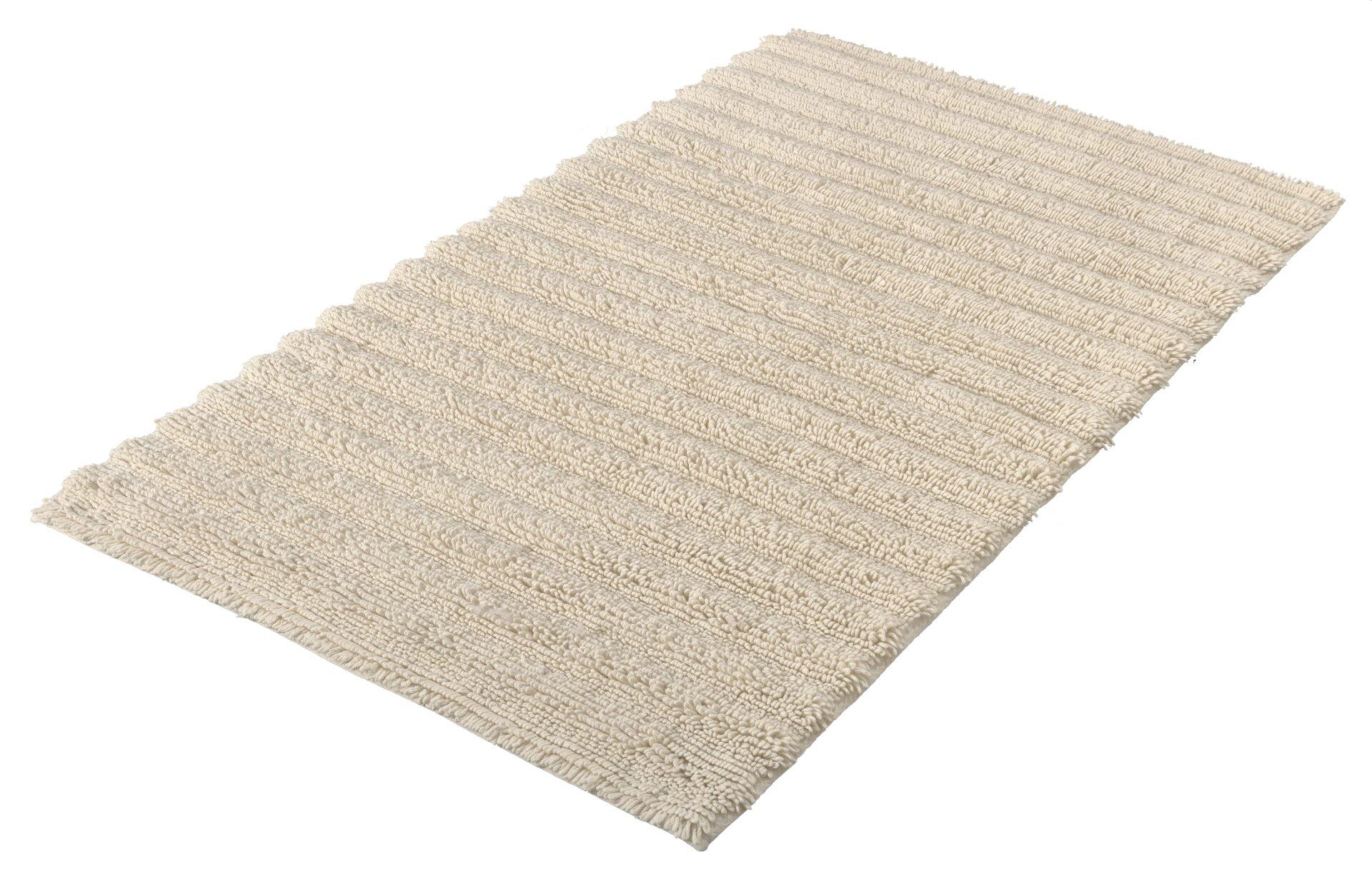 Flauschiger Badteppich Yara aus 100% Baumwolle mit vertikaler Streifenstruktur, präsentiert auf erhöhtem Untergrund zur Darstellung der Textur und des Volumens.