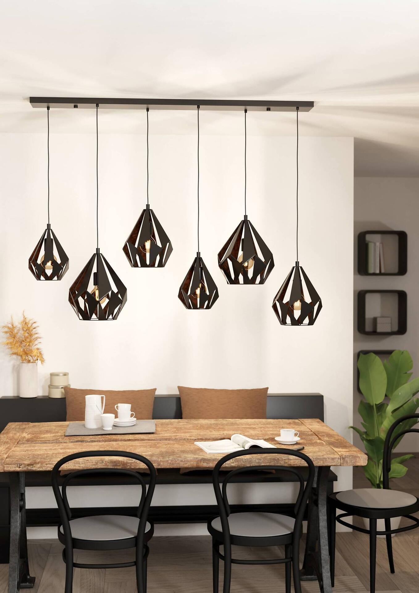 Pendelleuchte Carlton 1 mit fünf schwarzen, geometrischen Schirmen im industriellen Stil, die durch Löcher in der rautenförmigen Struktur Licht abstrahlen, dargestellt über einem Holztisch.