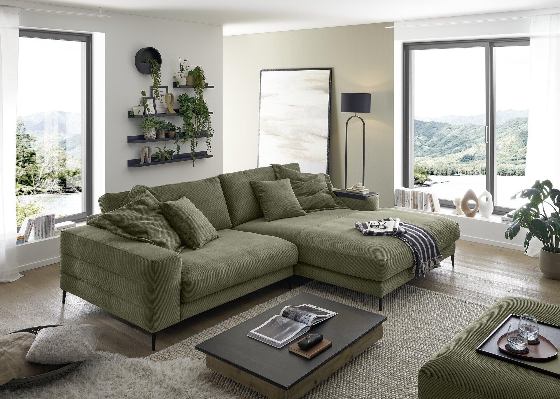 Polstergarnitur Badia Base 2.0, L-förmige Couch in Grünton mit niedriger Sitzhöhe und Armlehnen, dargestellt in einem stilvollen Wohnzimmer.