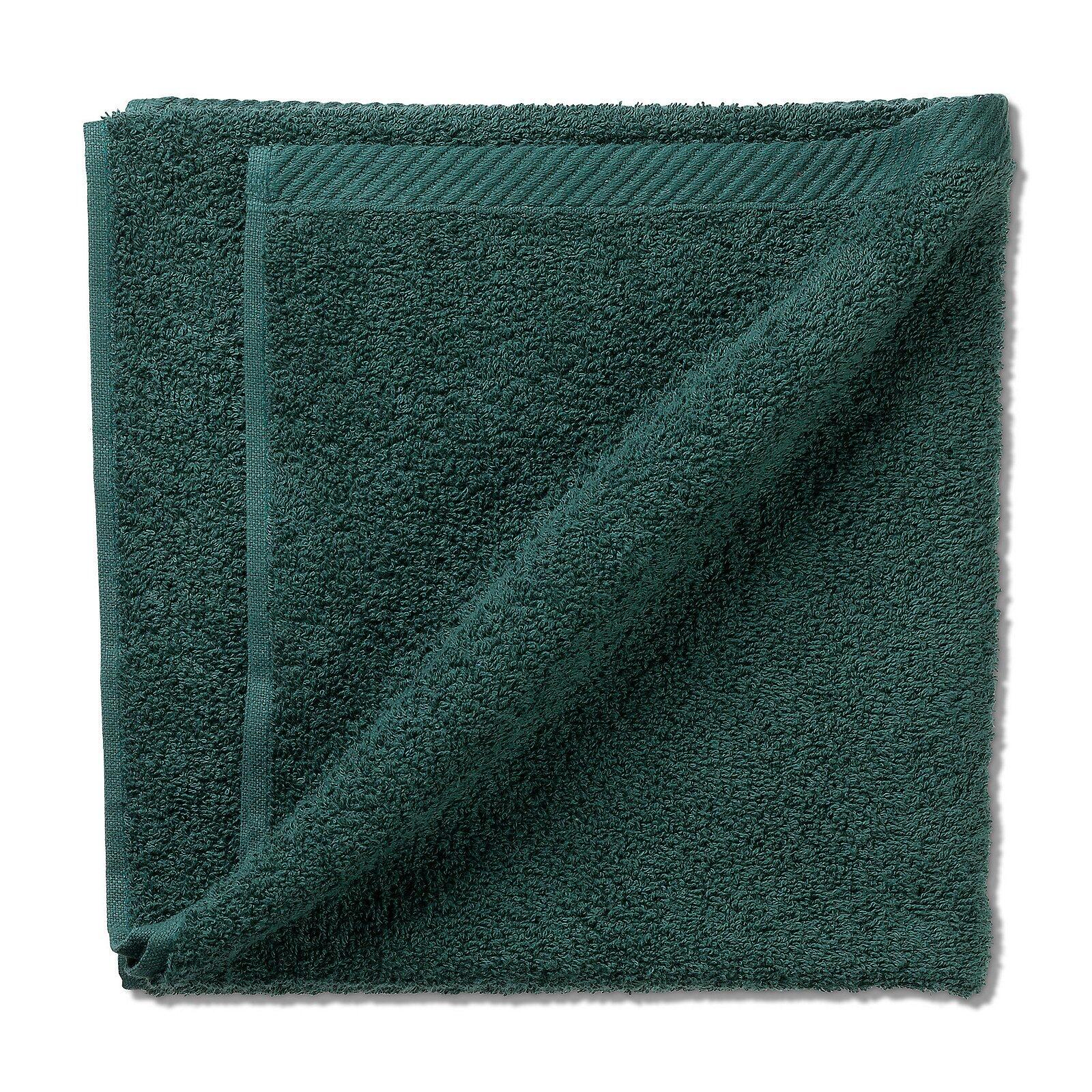 Dunkelgrünes Ladessa Handtuch mit flauschiger Flanellstruktur, diagonal gefaltet und von oben fotografiert, um die Textur und den hellen Saum zu zeigen.