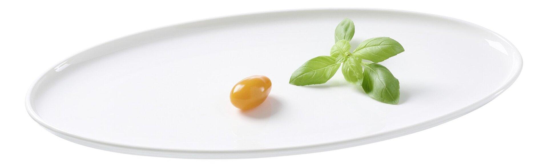 Platte Skagen, spülmaschinenfest, zeigt eine einzelne Kirschtomate und Basilikumblätter auf einem Teller vor weißem Hintergrund.