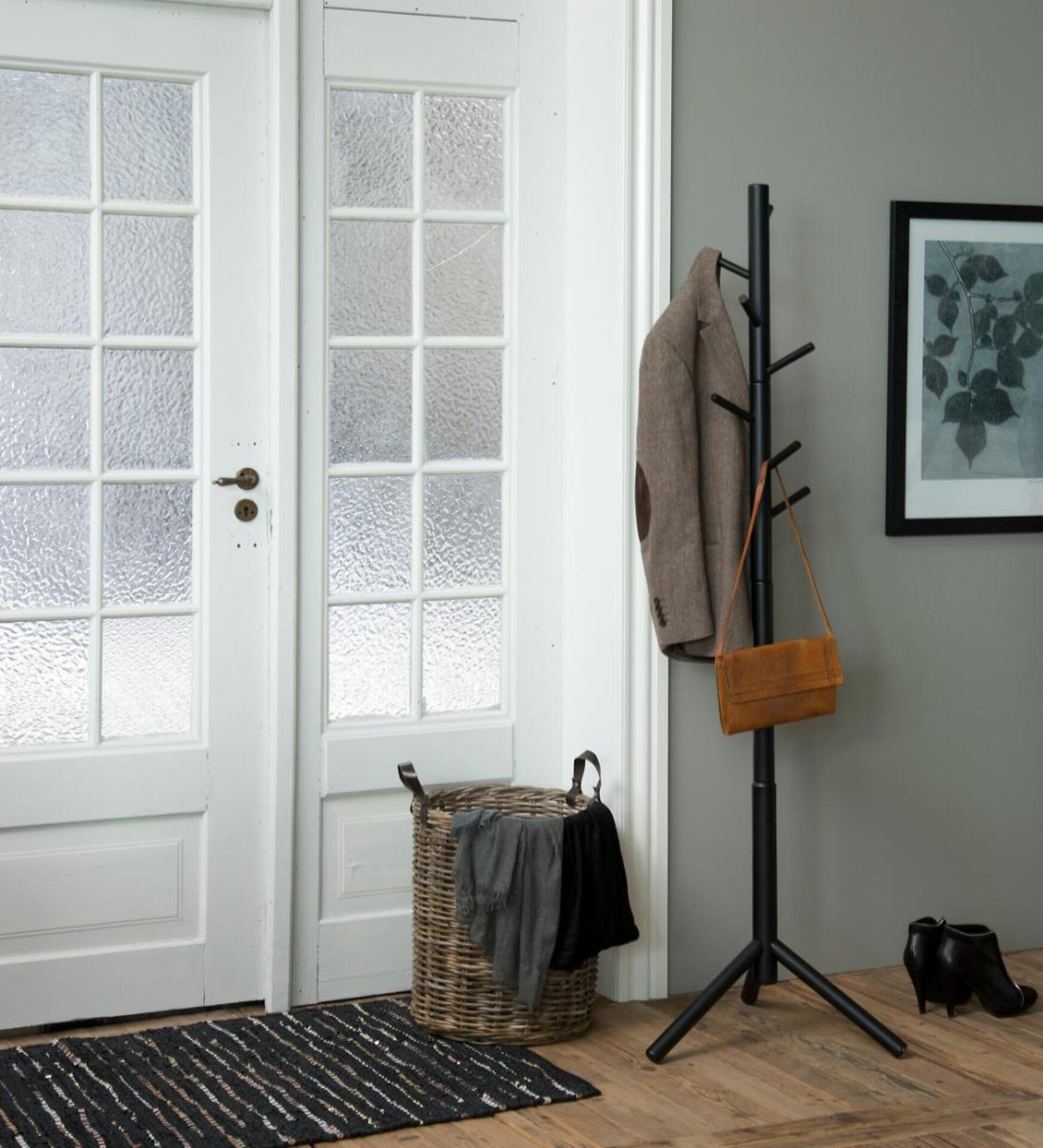 Kleiderständer Bremen mit asymmetrischem Design und gebogenen Haken, an denen Mantel und Handtasche hängen.