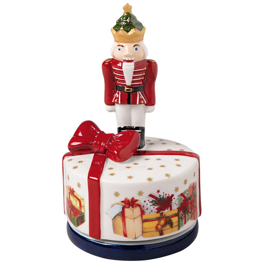Nussknacker "Nostalgic Melody" von Villeroy & Boch mit aufwendlicher Uniform, Tannenzapfen und dekorativem Sockel mit weihnachtlichen Motiven, frontal aufgenommen und mit Anspielung auf eine Drehfunktion dargestellt.