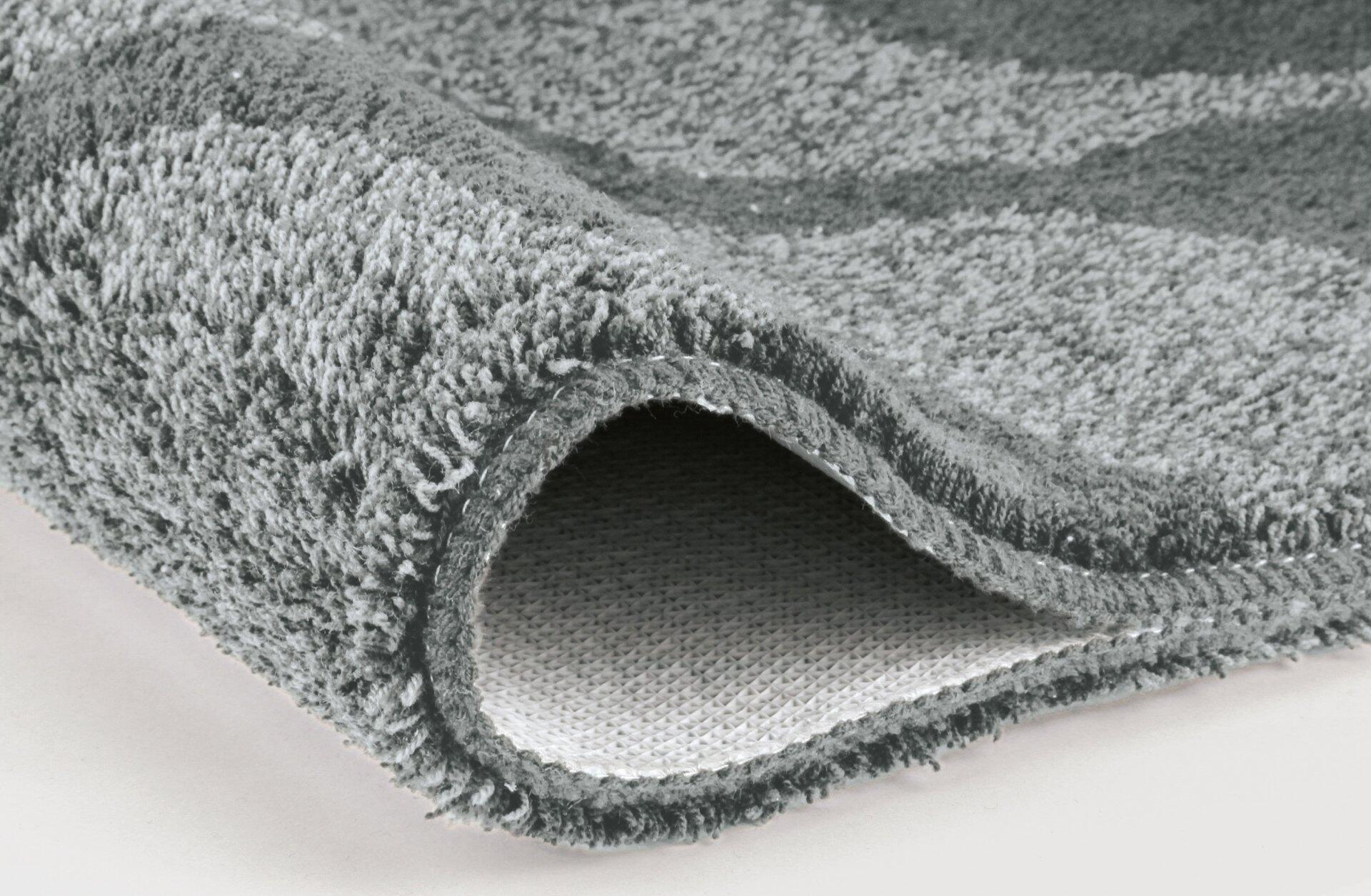 WC-Vorleger Onda: Detailaufnahme der aufgerollten Textur mit dichtem, flaumigem Obermaterial und strukturierter Unterseite.