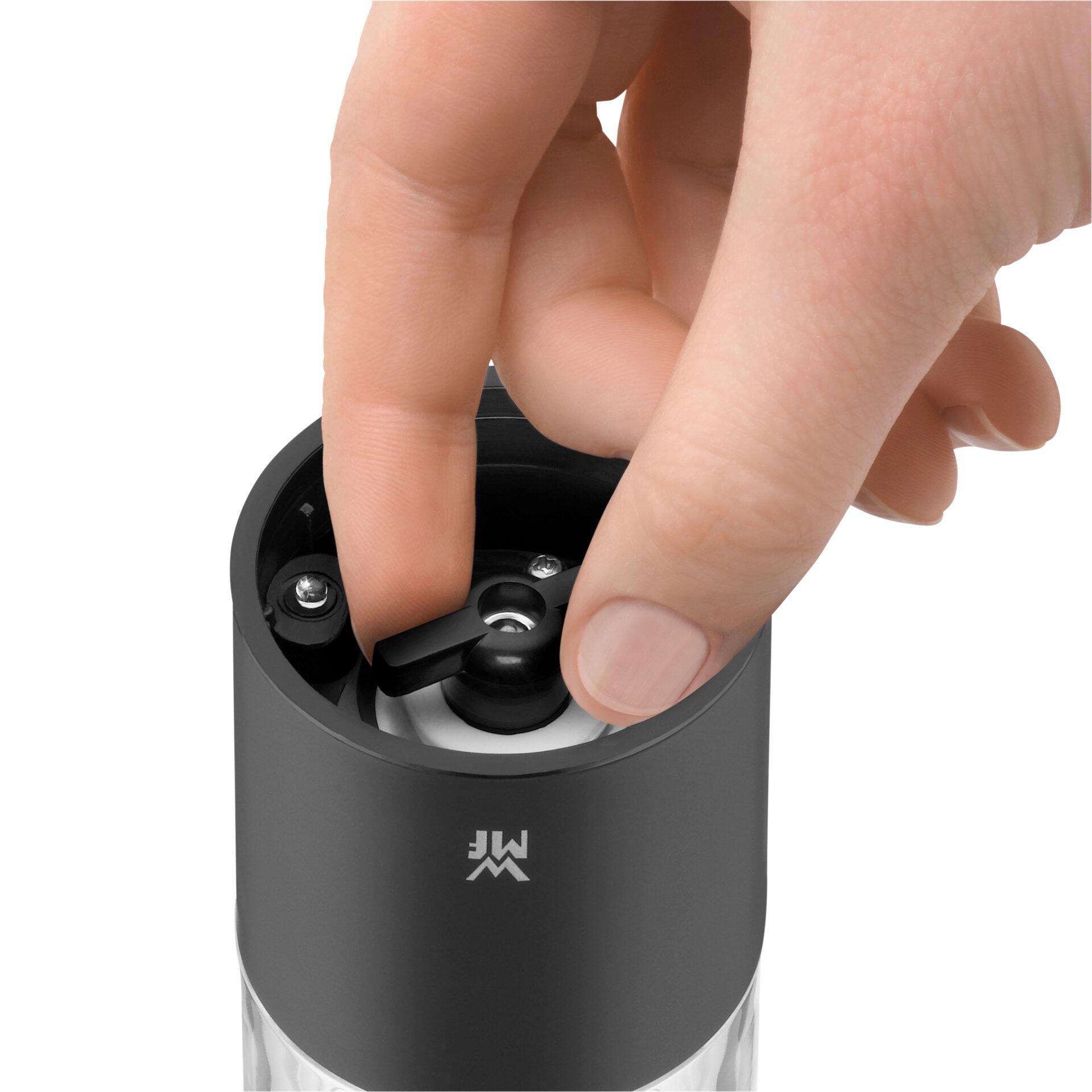 Elektrische WMF Kaffeemühle, Detailaufnahme von oben, zeigt Hand beim Entnehmen des gemahlenen Kaffees und das transparente Gehäuse mit den sichtbaren Mahlwerken.