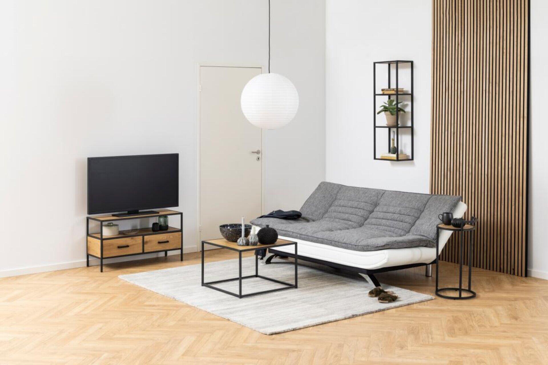 Bettcouch Faith mit grauer Mikrofaserbezug und Chromstahlgestell, in einer dreiviertel Ansicht dargestellt, die die integrierte Lendenwirbelstütze und die erhöhte Position des Sofas zeigt.