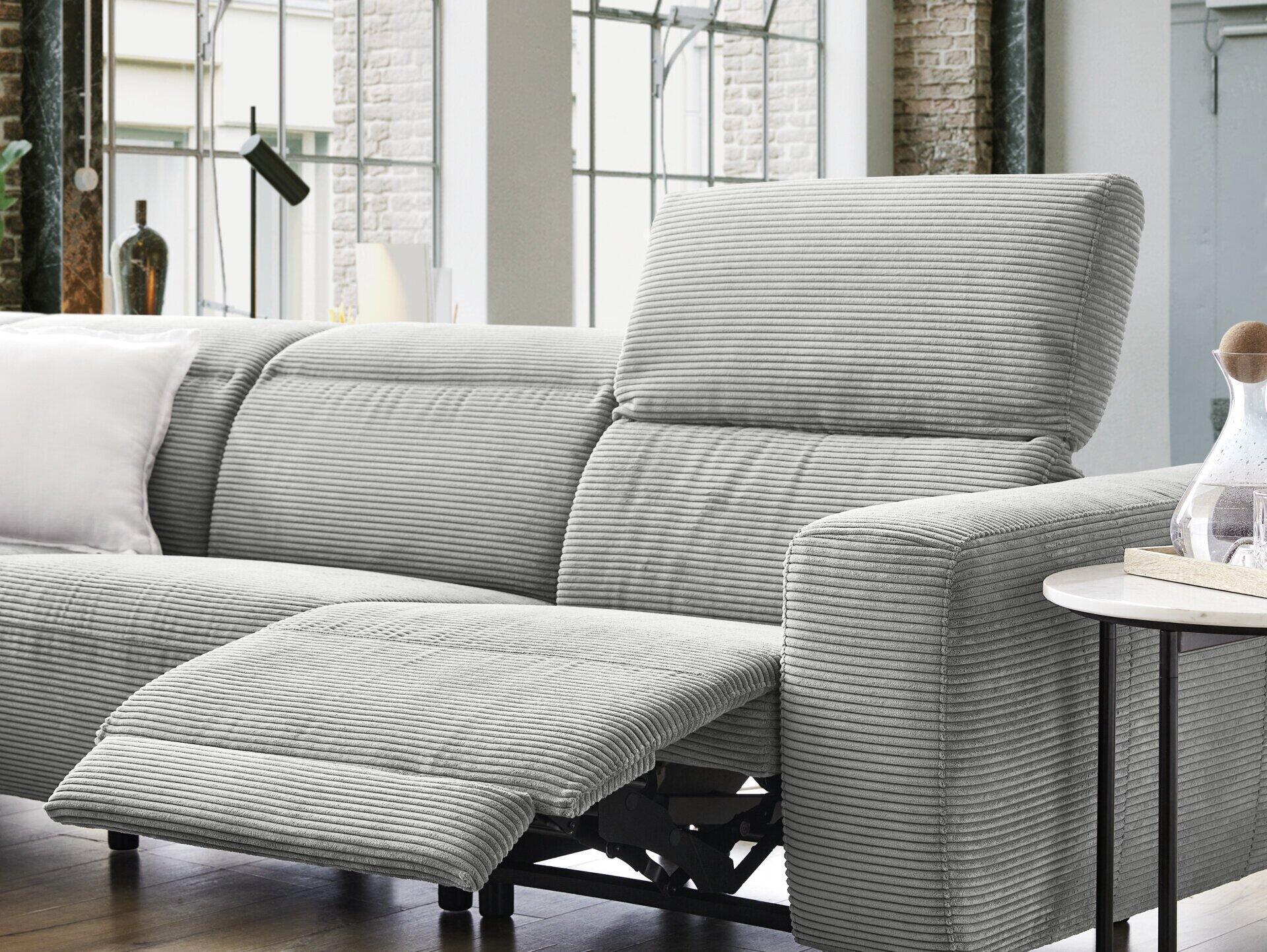 Graues Ecksofa Pure 902 2.0 mit Cordstoffbezug und ausgefahrener Fußstütze, die den Mechanismus für die Kopfteilverstellung mit schwarzem Metallrahmen zeigt.