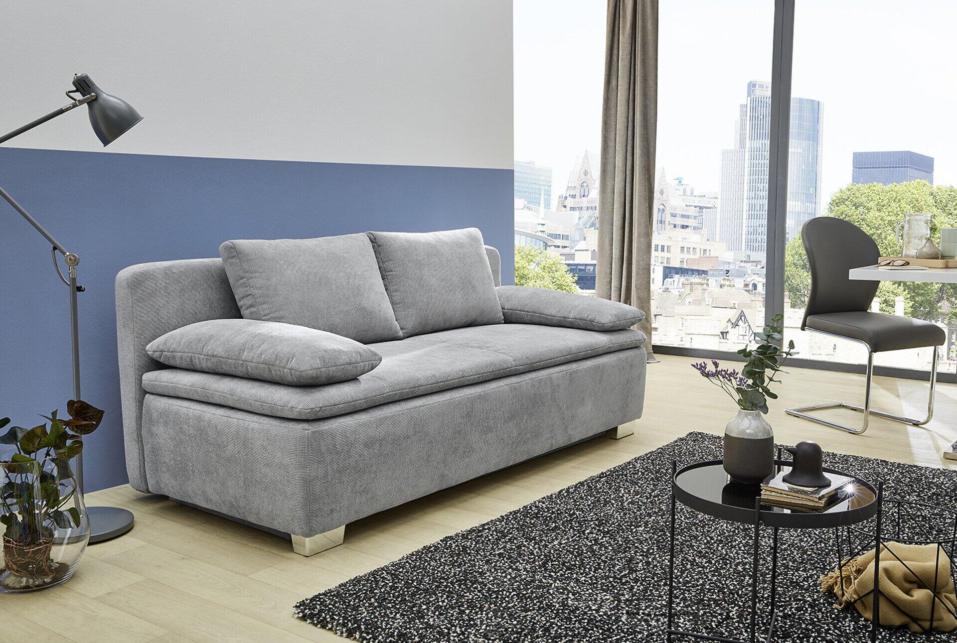 Graues modulares Schlafsofa "Duett" mit abgerundeten Formen und chromfarbenen Füßen, präsentiert in leicht erhöhter Perspektive in einer stilvollen Innenraumumgebung.