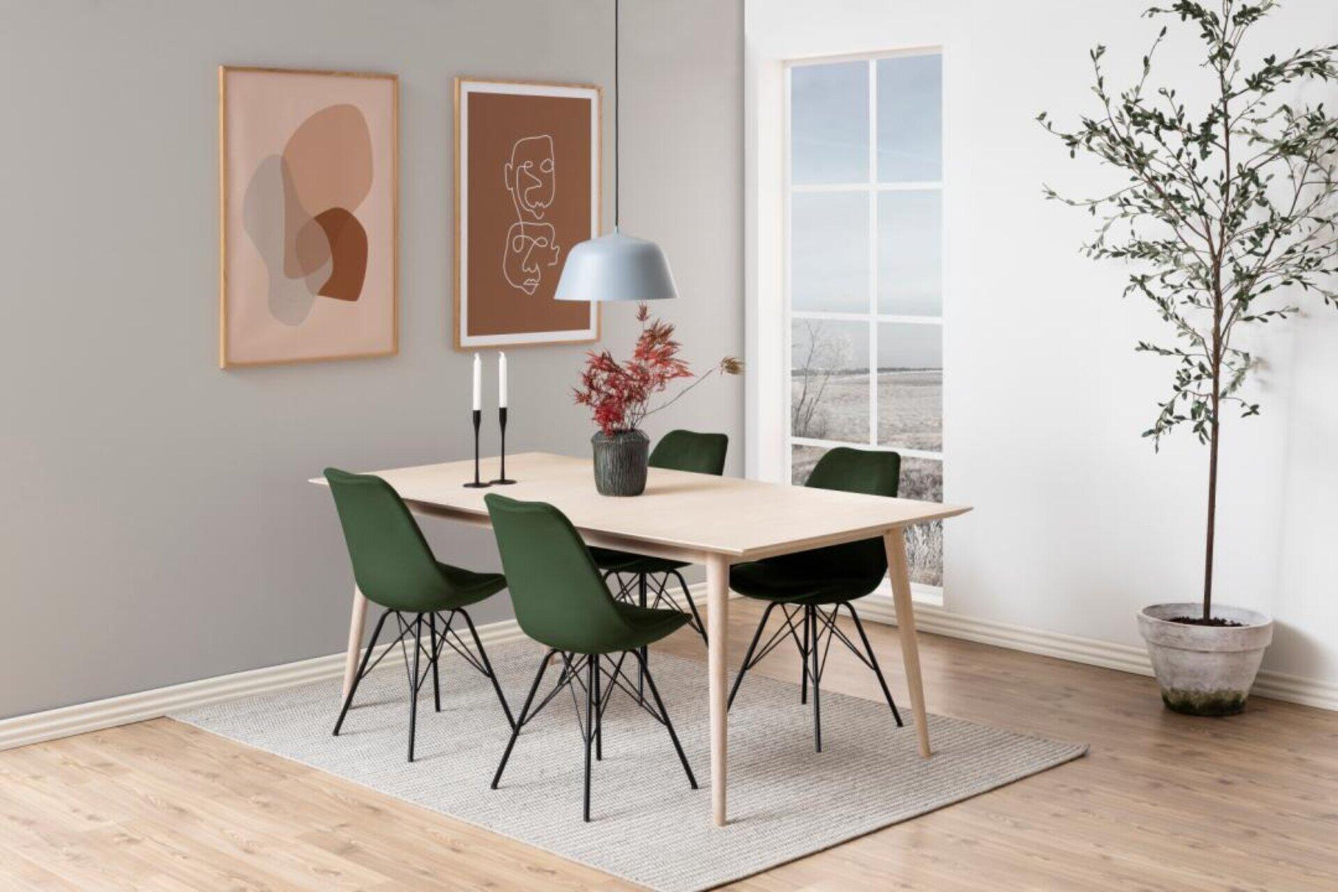Esszimmerstuhl Eris mit dunkelgrüner Sitzfläche und filigranen schwarzen Metallbeinen, dargestellt in einer Gesamtsicht einer modernen Essgruppe mit Tisch und Teppich.