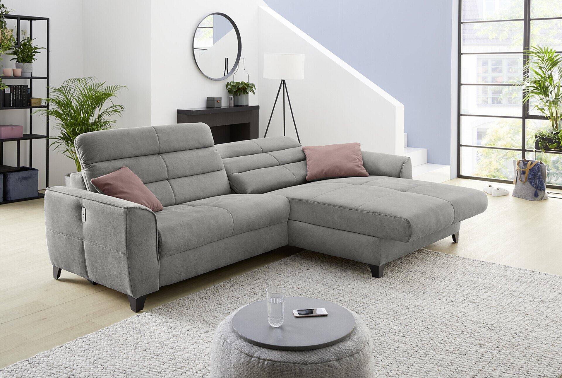 Wohnlandschaft Double One mit abklappbarer Liegefläche in der rechten Ecke und samtartigen rosafarbenen Kissen, präsentiert in einem stilvollen Wohnzimmer.