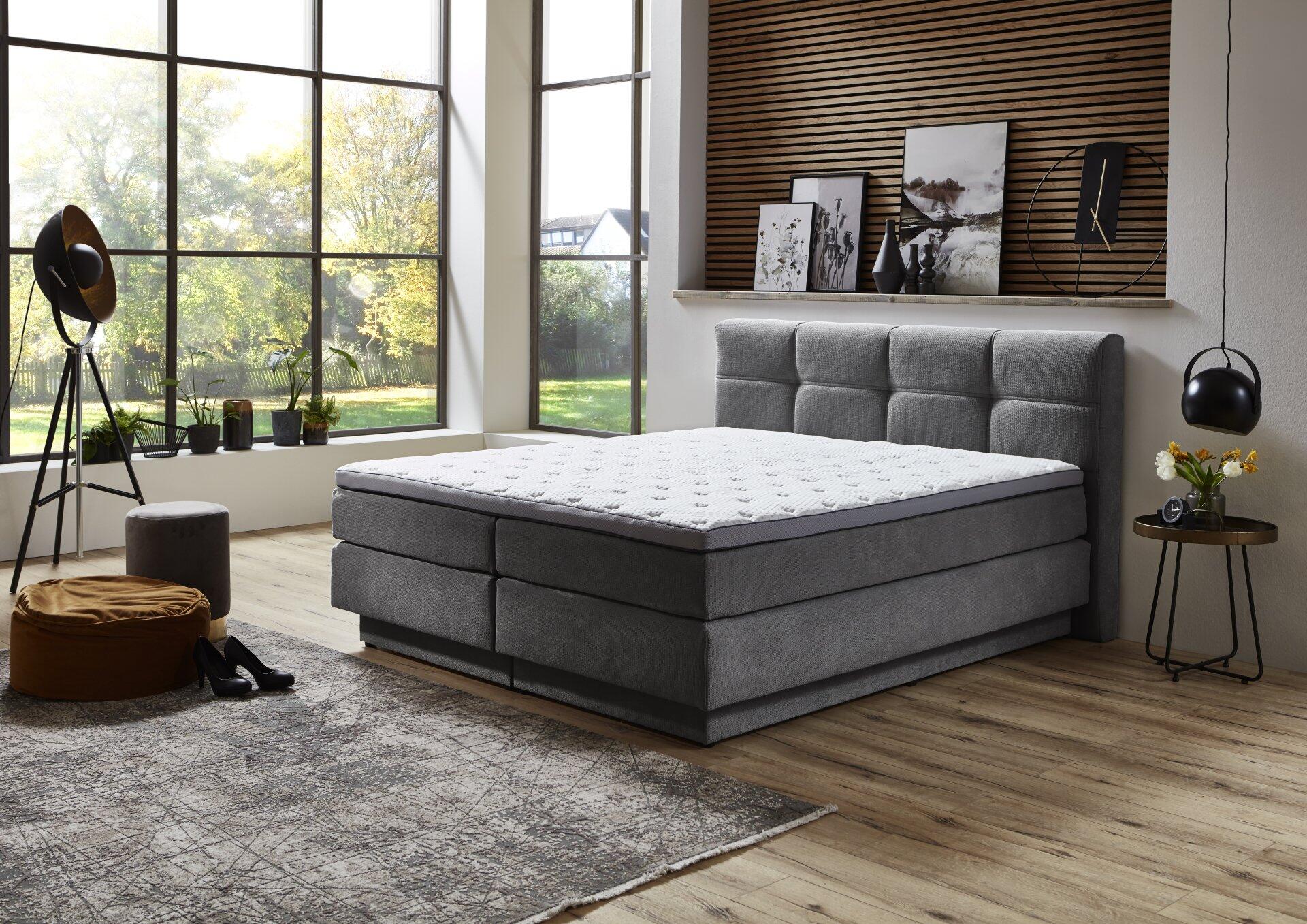 Boxspringbett Portage BX2110 in grau mit horizontalen Kissensteifen, niedrigem Bettrahmen und Schubladen für zusätzlichen Stauraum.