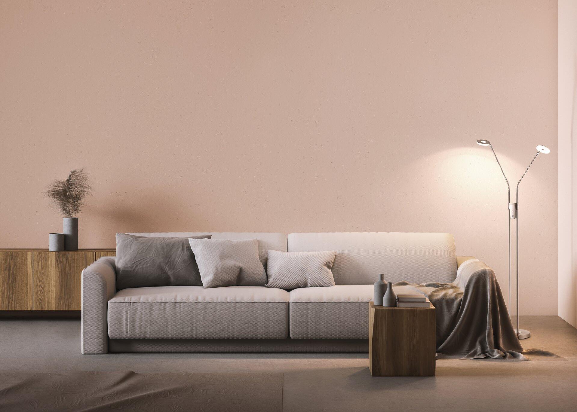 Stehleuchte Dent als silberfarbene Stehlampe neben einem Holz-Beistelltisch in einem modernen Wohnzimmer.