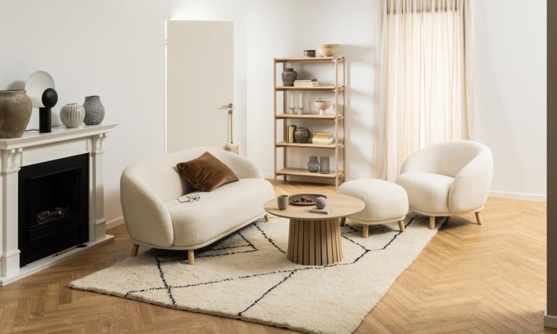 Regal Braidwood aus Holz, gefüllt mit dekorativen Objekten, im Hintergrund eines hellen Wohnzimmers mit Sofa, Sessel und Kamin.