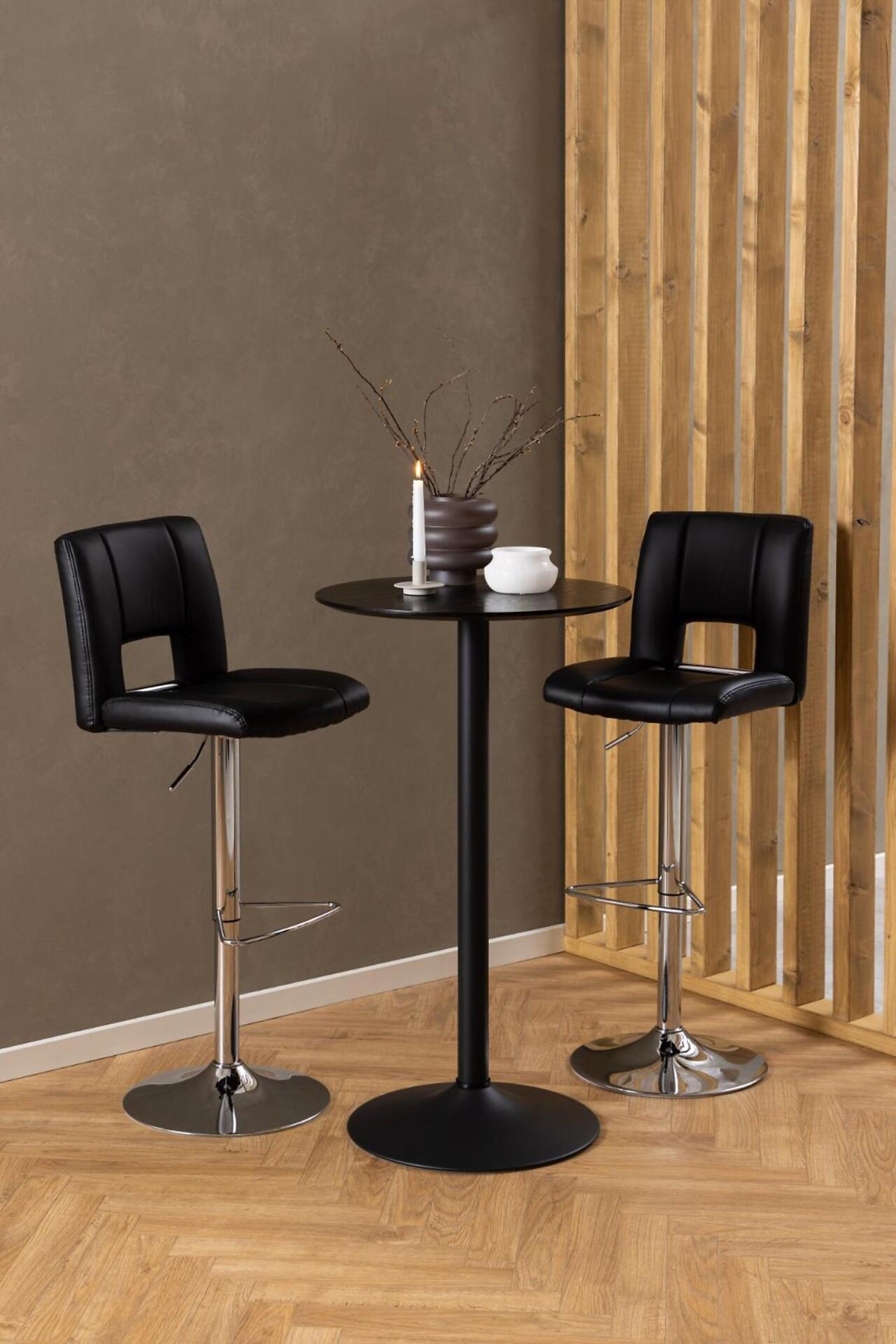 Bartisch Ibiza mit zwei Barhockern, Fußring und verstellbarer Höhe, vor einer rustikalen Wand.