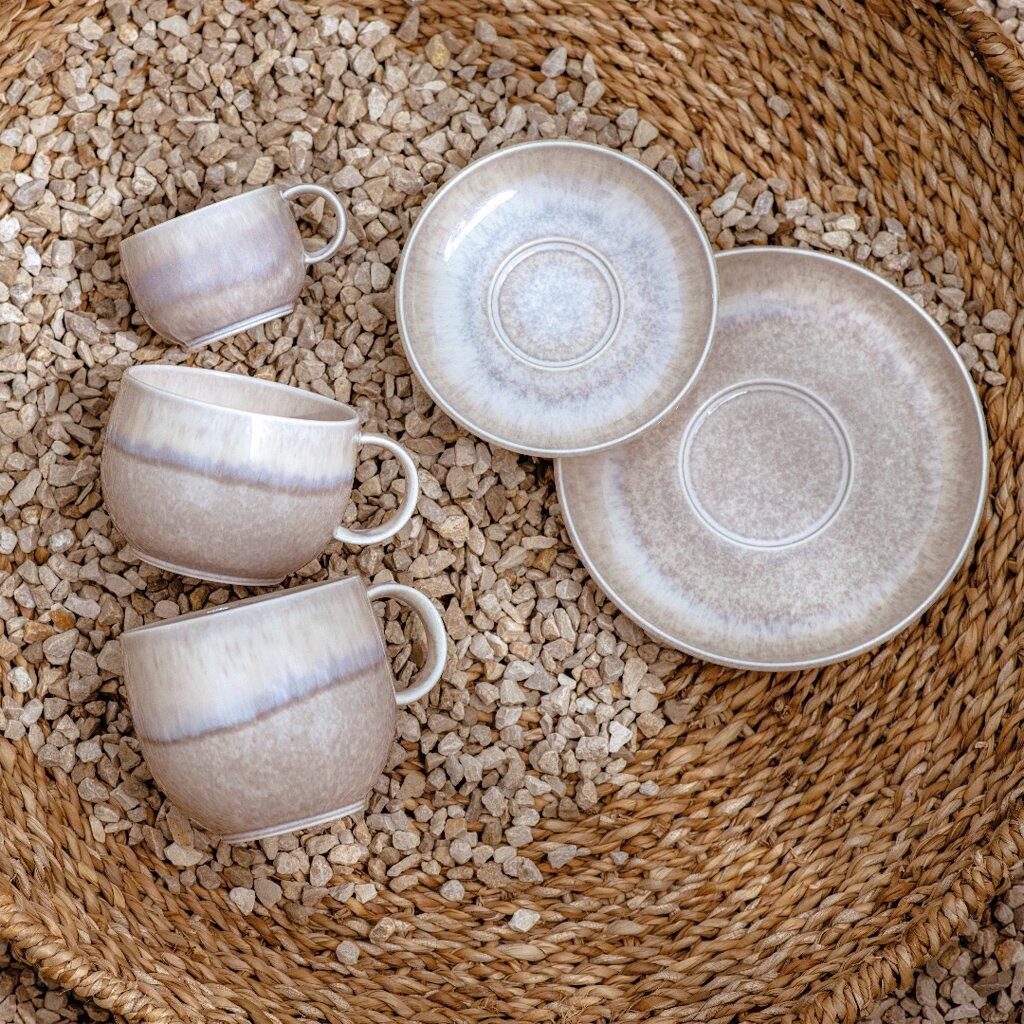 Espressountertasse Perlemor Sand aus Keramik mit leicht gewölbtem Rand auf einer dekorativen Rattan-Unterlage.