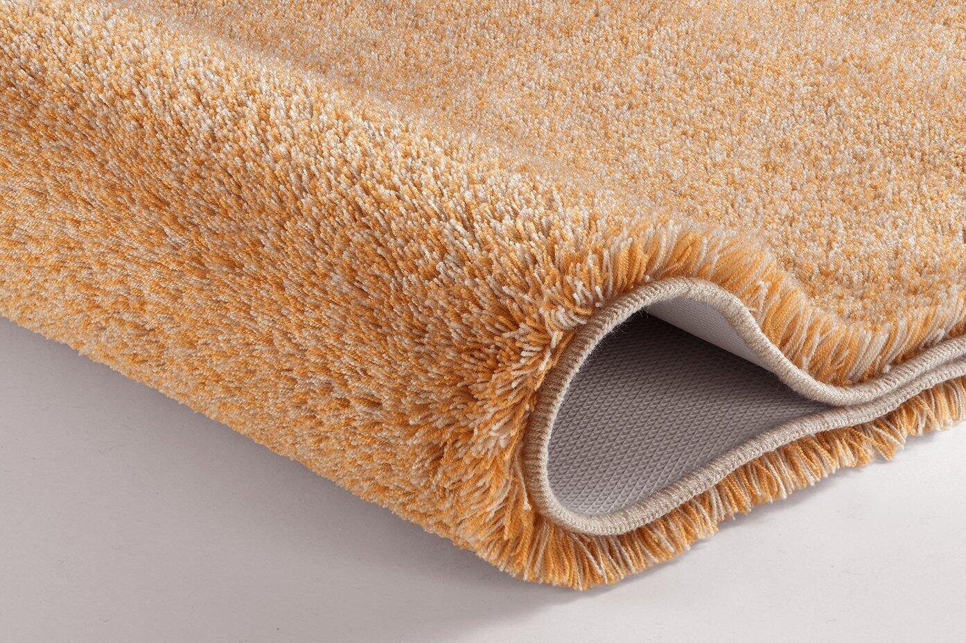 Relax Badteppich-Set im Schnitt mit hellgelbem, flauschigem Flor und hellgrauer Unterseite, zeigt gefaltete Kante zur Veranschaulichung der Dicke und Schichtung.