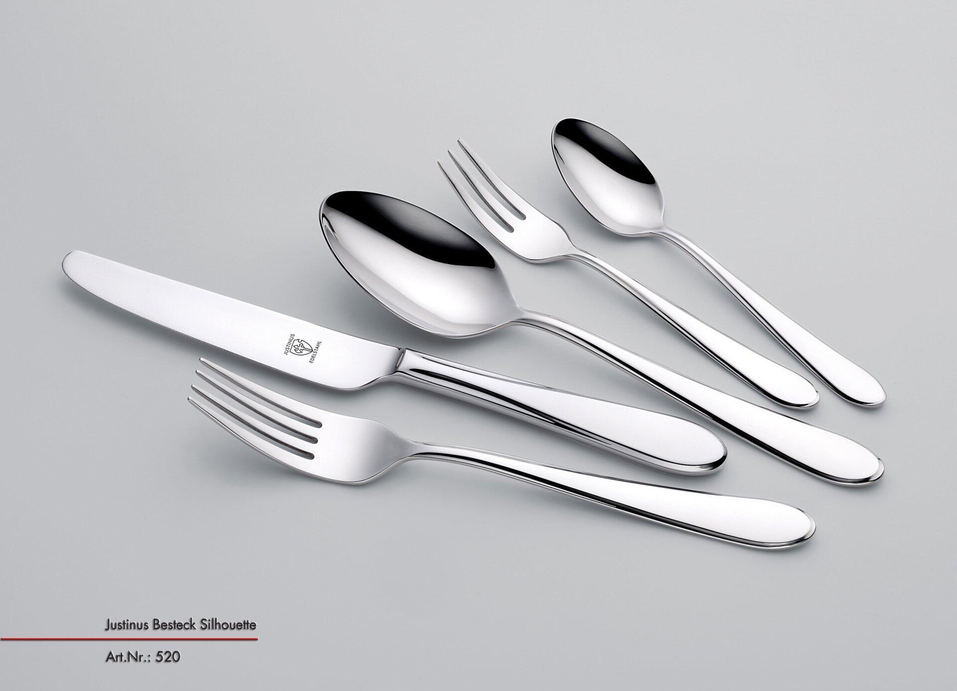 Draufsicht auf ein Komplett-Besteck "Silhouette" aus Edelstahl, bestehend aus Esslöffel, Gabel mit vier Zinken, Essmesser und Dessertbesteck, wobei die elegante Griffgestaltung und das kleine Logo auf der Gabel erkennbar sind.