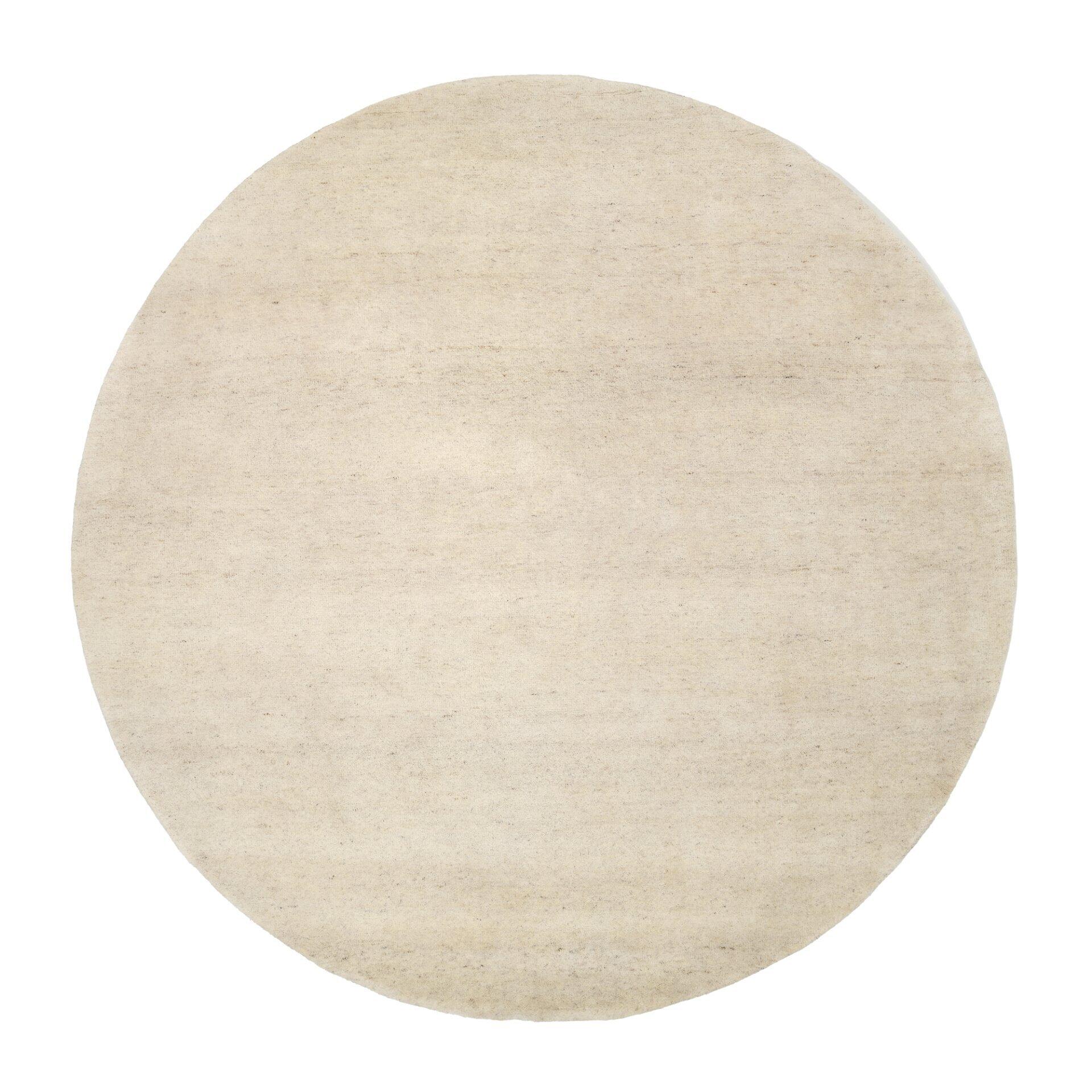 Runder, hellbeige Handknüpfteppich Assos mit sichtbarer Wolltextur vor weißem Hintergrund.