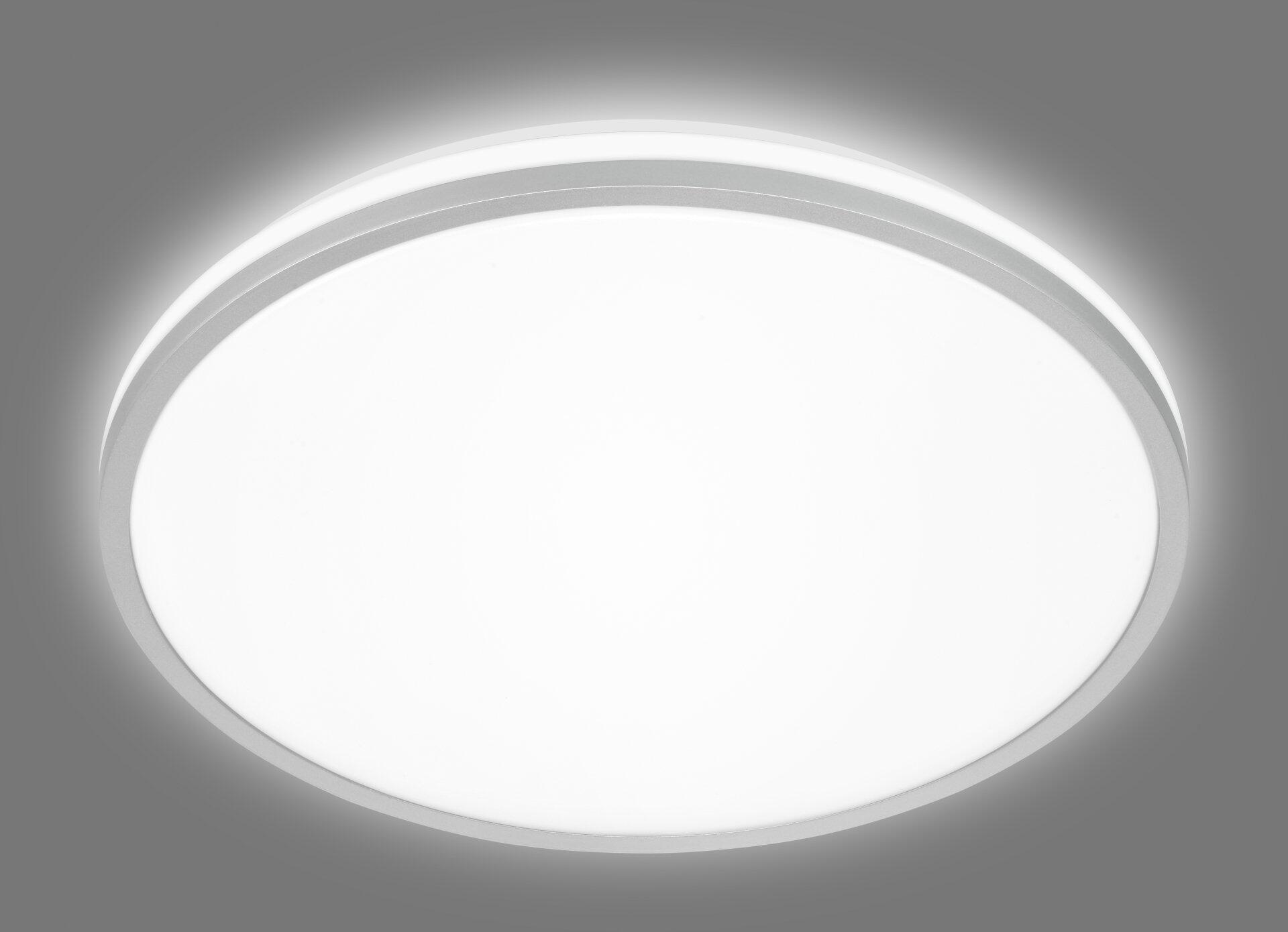 Die runde Wand- und Deckenleuchte Lana a mit Ø33cm, strahlt in Frontalperspektive ein helles, gleichmäßiges Licht aus und besticht durch ihre schlichte, moderne Form mit weißer Leuchtfläche und silbernem Rahmen.
