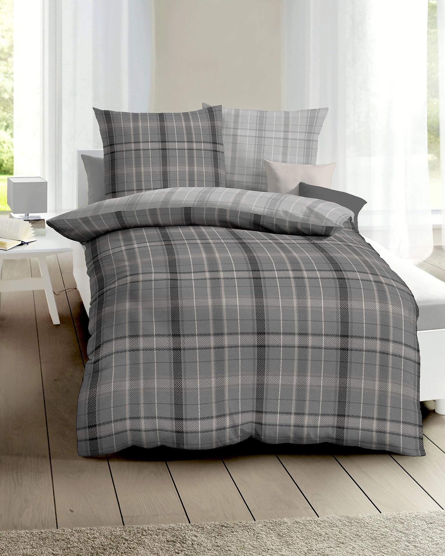Bettwäsche Villa in anthrazit mit grauem Karomuster und zwei 80x80 cm Kissen auf einem frontal dargestellten Bett.