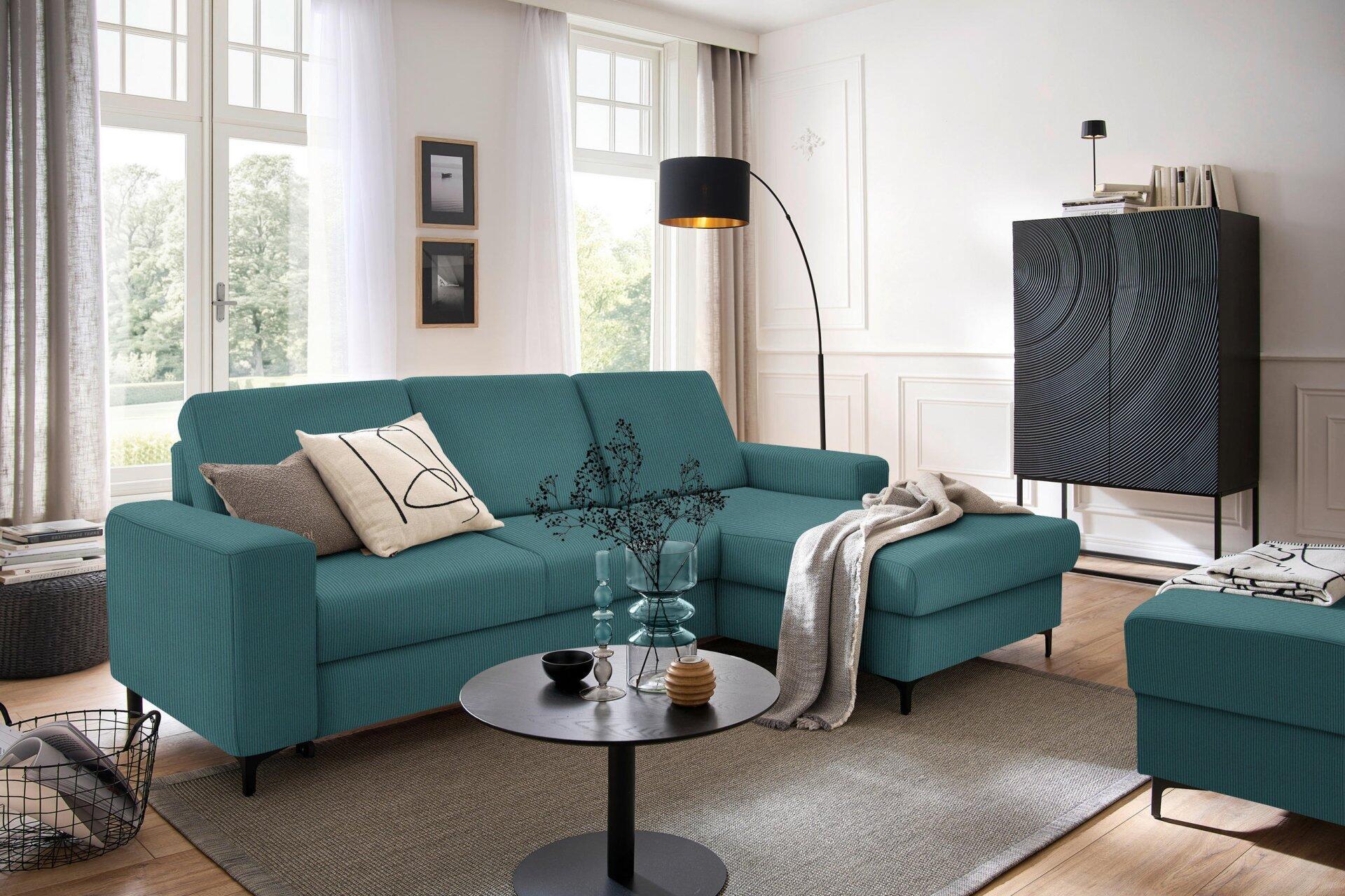 Ecksofa Balina in Türkisblau mit hochklappbarer Liegefläche und Winkelfüßen, dargestellt in einer 3/4-Ansicht in einer modernen Wohnszene.