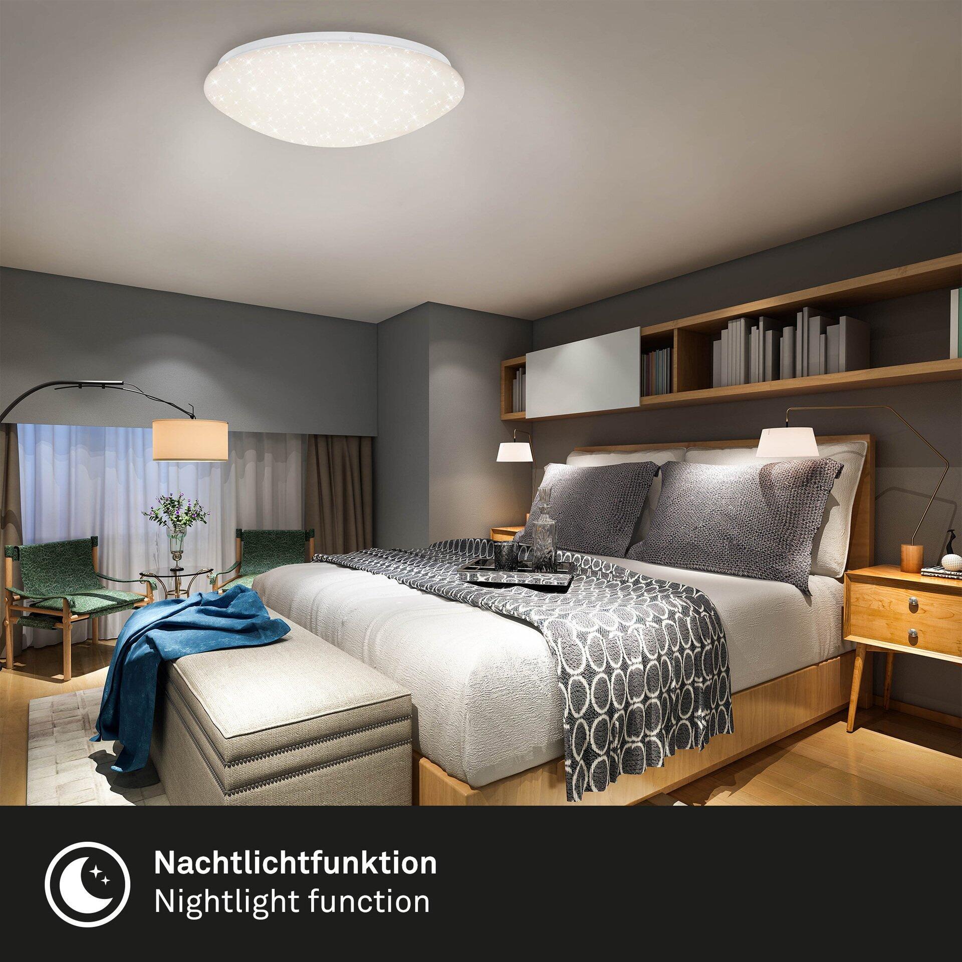 Wand- und Deckenleuchte BRILO mit integrierter Nachtlichtfunktion, beleuchtet ein luxuriöses Schlafzimmer mit Bett, Nachttischen und Sitzbank.