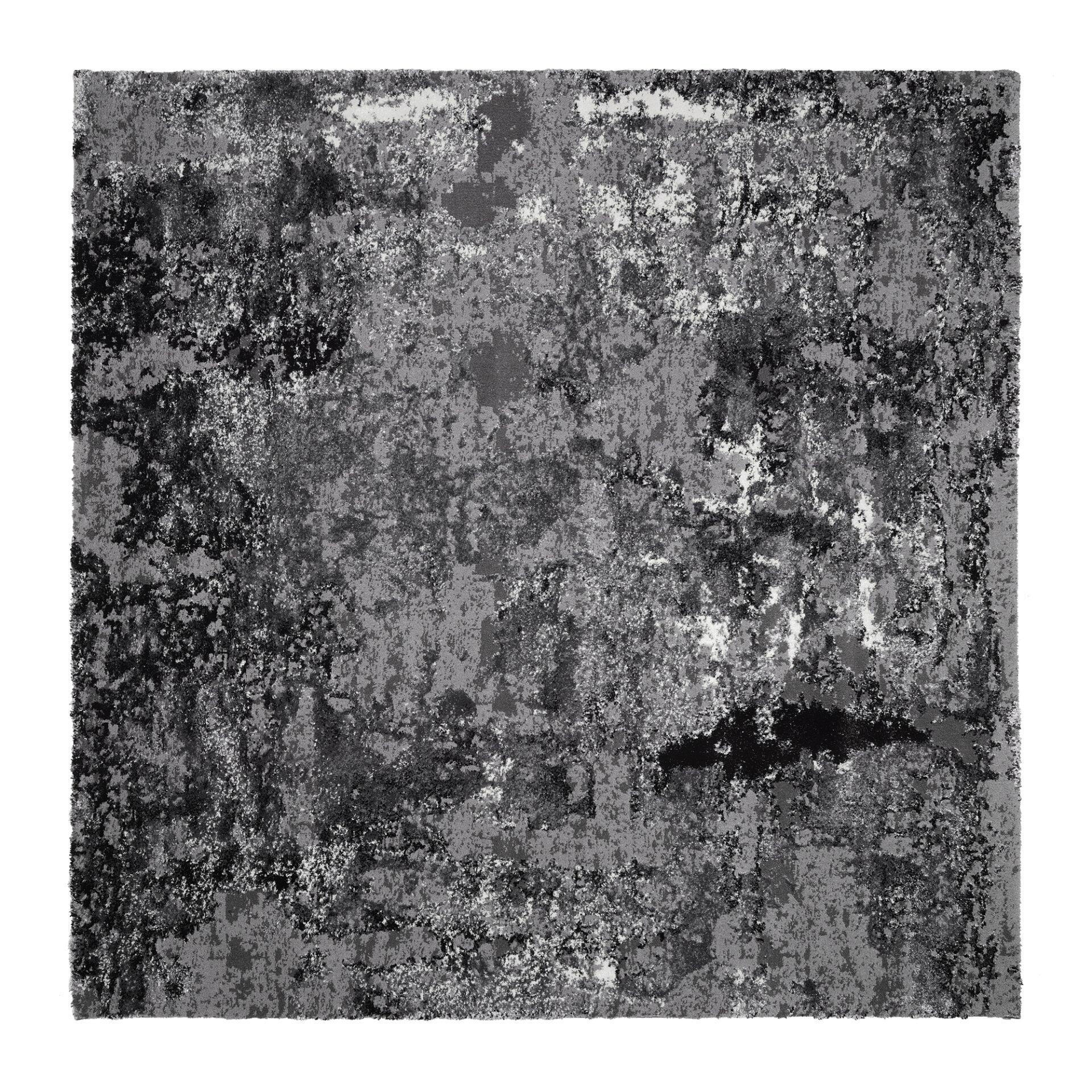 Detailaufnahme der strukturierten Oberfläche des Maschinenwebteppichs Koralka, die durch ein unregelmäßiges Muster aus hellen und dunklen Flecken eine fast abstrakte Textur erzeugt.