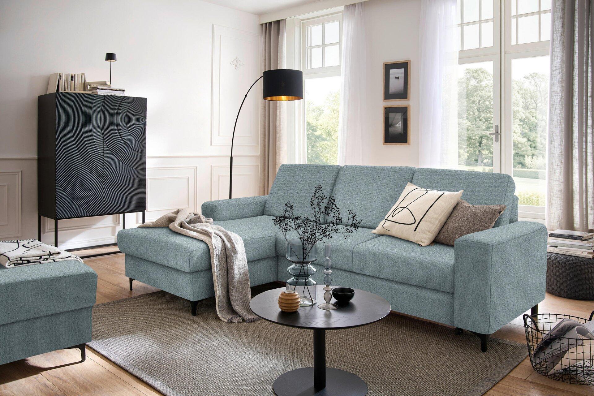 Helles Ecksofa Balina mit L-Form, breiten Armlehnen und Winkelfüßen in Schwarz, in einer Drei-Viertel-Ansicht im modernen Wohnzimmer.