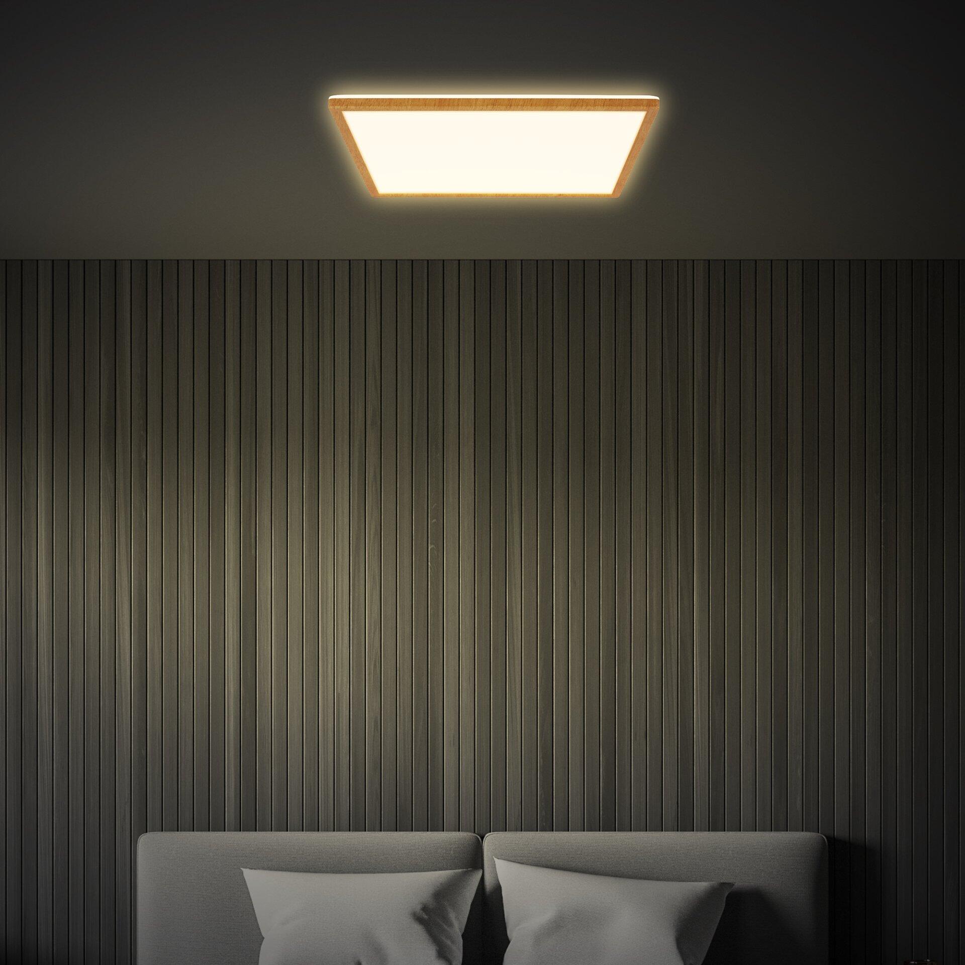 Panel Tava Wood LED Deckenleuchte mit quadratischem Design und goldener Umrandung, beleuchtet einen Wandbereich mit vertikalen Holzlamellen.