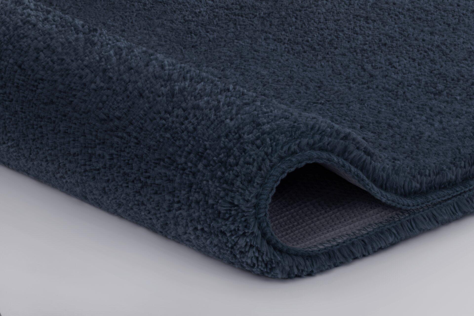 Dunkelblauer Badteppich Meadow mit hohem, dichtem Flor und strukturierter Rückseite, Detailaufnahme aus schräger Perspektive.