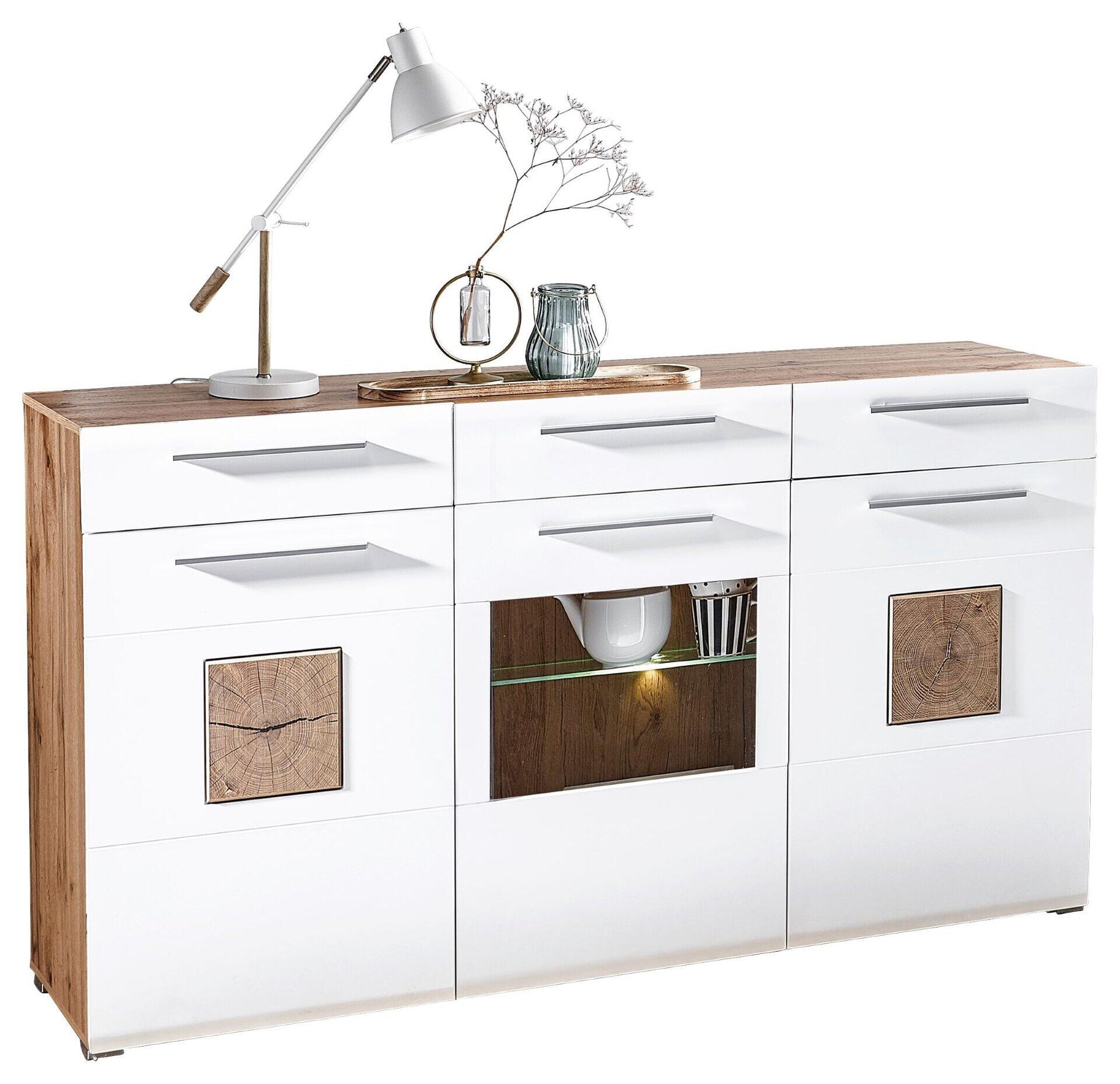 Weißes Sideboard Savona mit drei Schubladen, zwei Holztüren, einer Glastür und LED-Beleuchtung, aus der Vogelperspektive mit dekorativen Holzfurnier-Elementen und einer Vase mit Blumen.