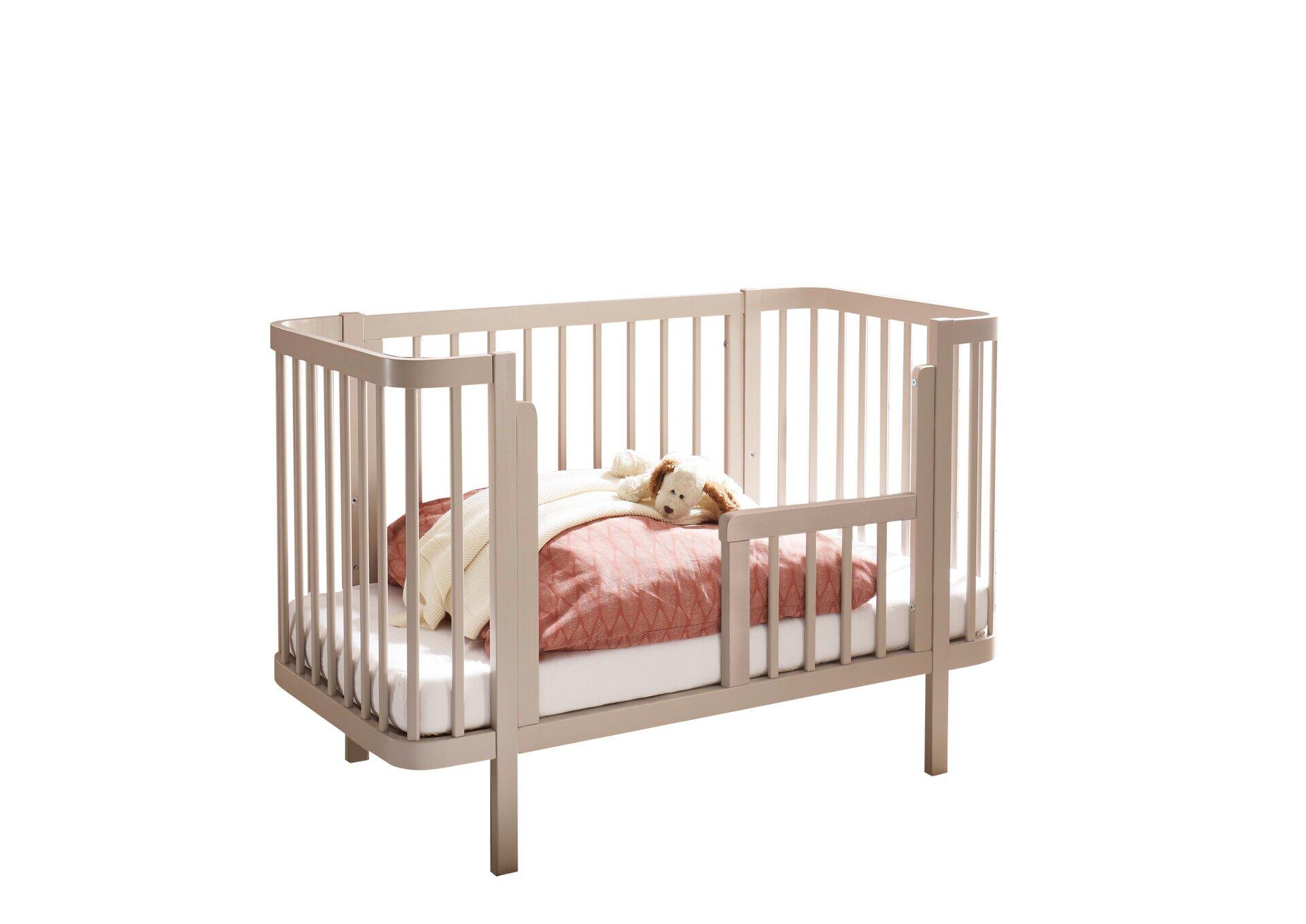 Babybett Peppini in hellgrau mit Umbauseite und Geländerfunktion, seitliche Ansicht.
