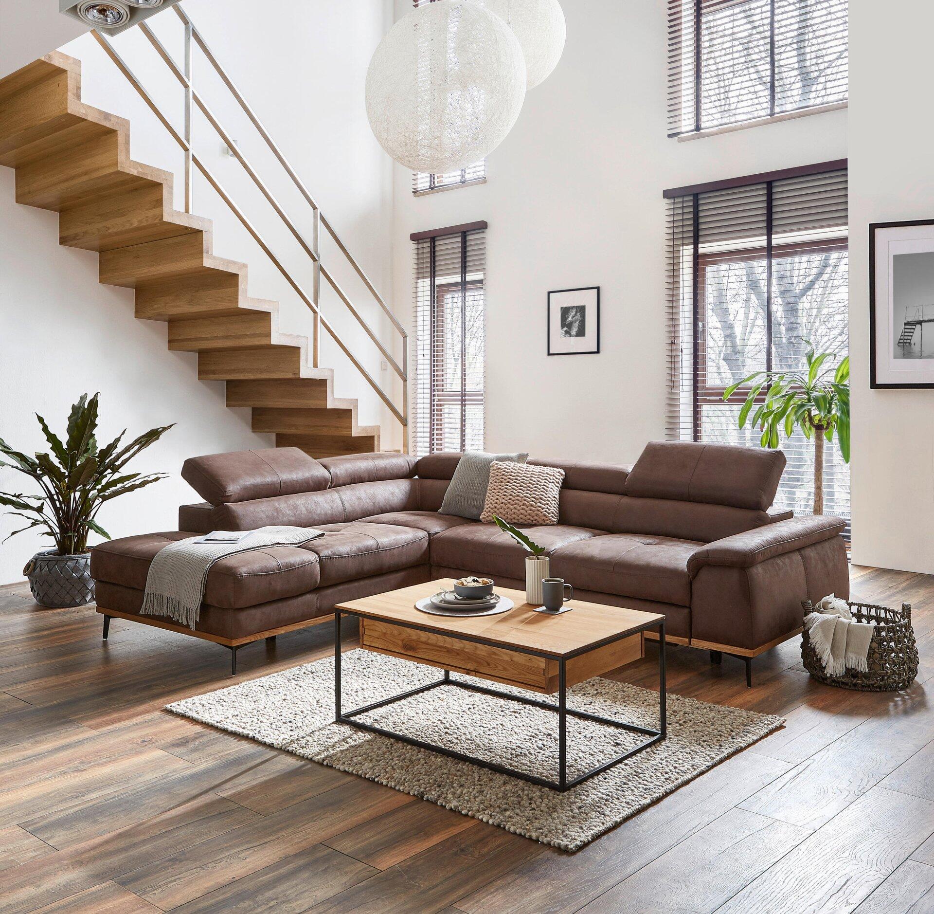 Couchtisch Patricia mit schwarzem Metallgestell und Schublade vor einer braunen Eckcouch in einem stilvoll eingerichteten Wohnzimmer.