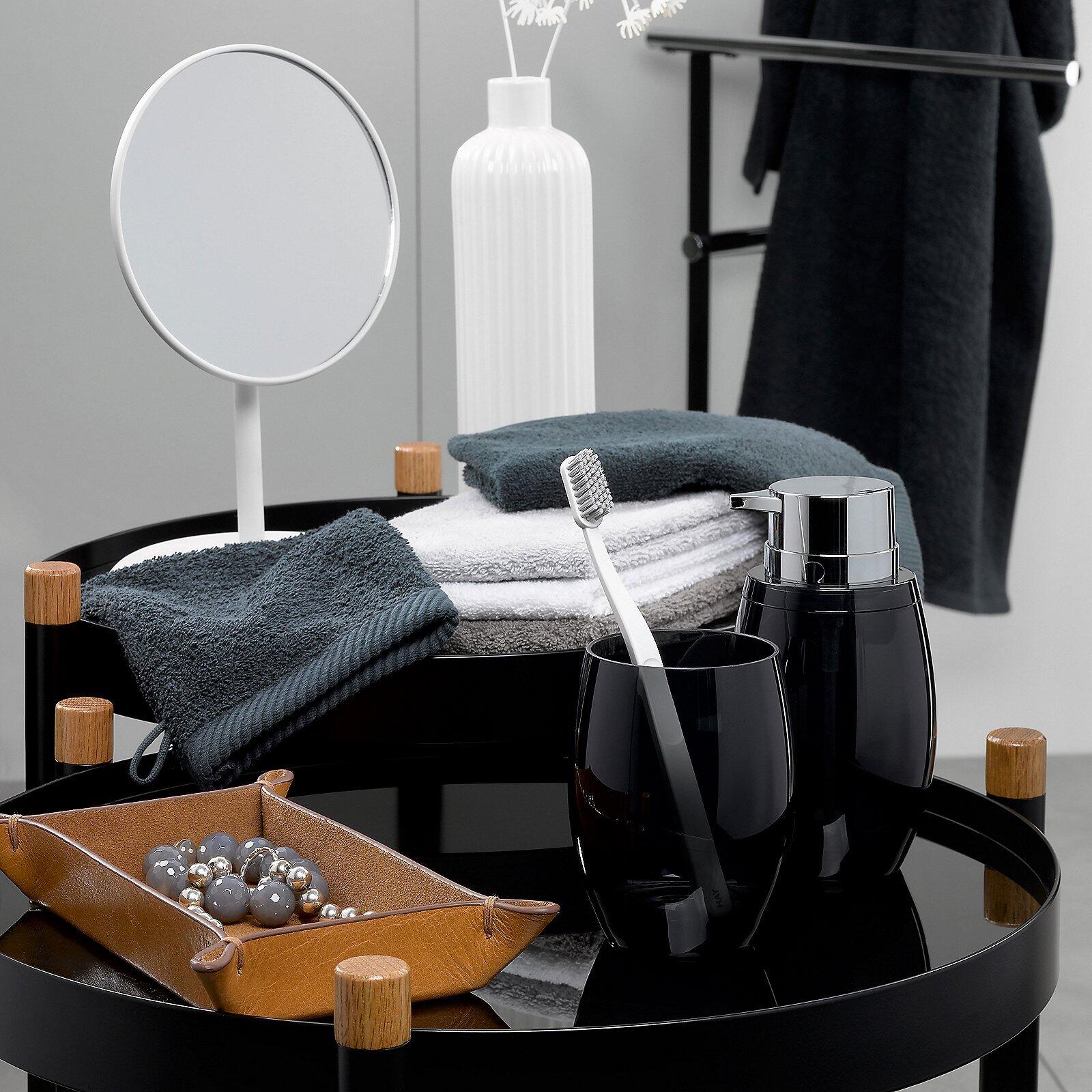 Ladessa Waschhandschuh auf einer runden Ablagefläche mit Tablett, Handtuch, Seifenspender und Accessoires.