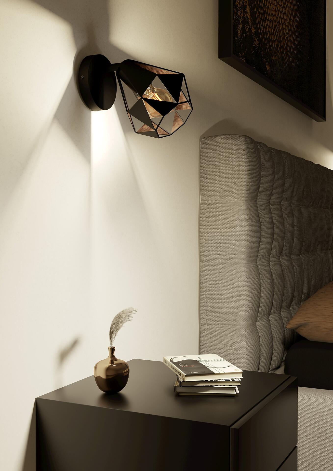 Schwarze Carlton 7 Wandlampe mit geometrischem Muster und warmem Licht, montiert an einer Wand, mit Blick auf Nachttisch und dekorative Elemente.